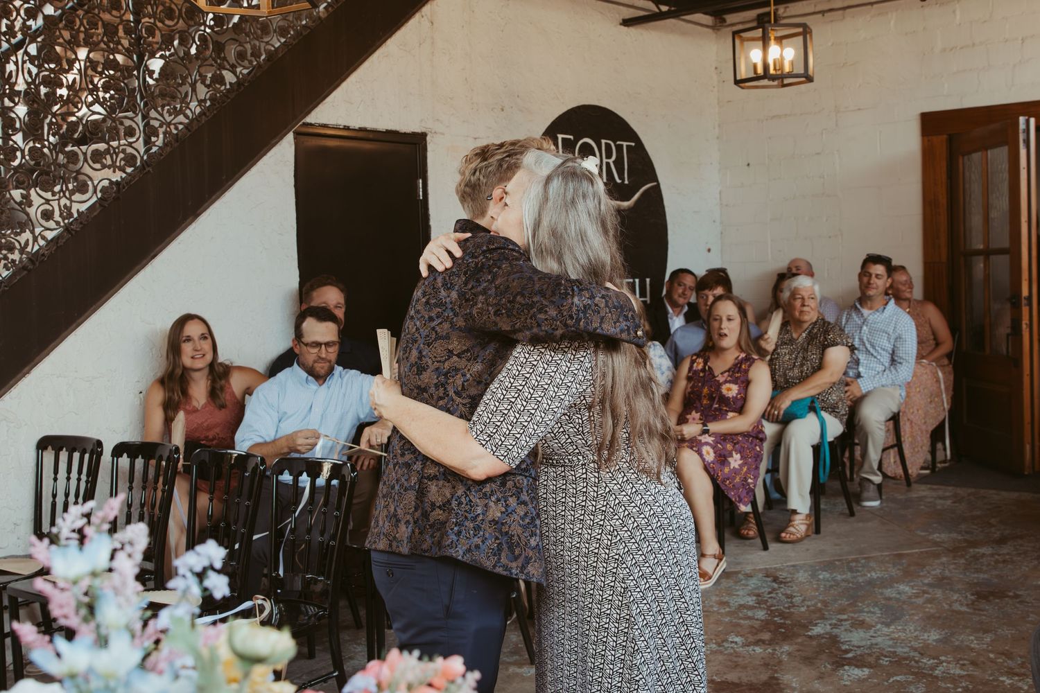 Wedding reception guests gathered at outdoor tables under string lights at a rustic venue.