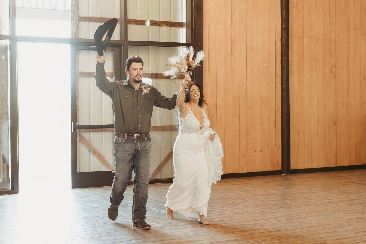 A couple dances together in an elegant wooden-floored room with natural light streaming through windows. Wedding photographer DFW
