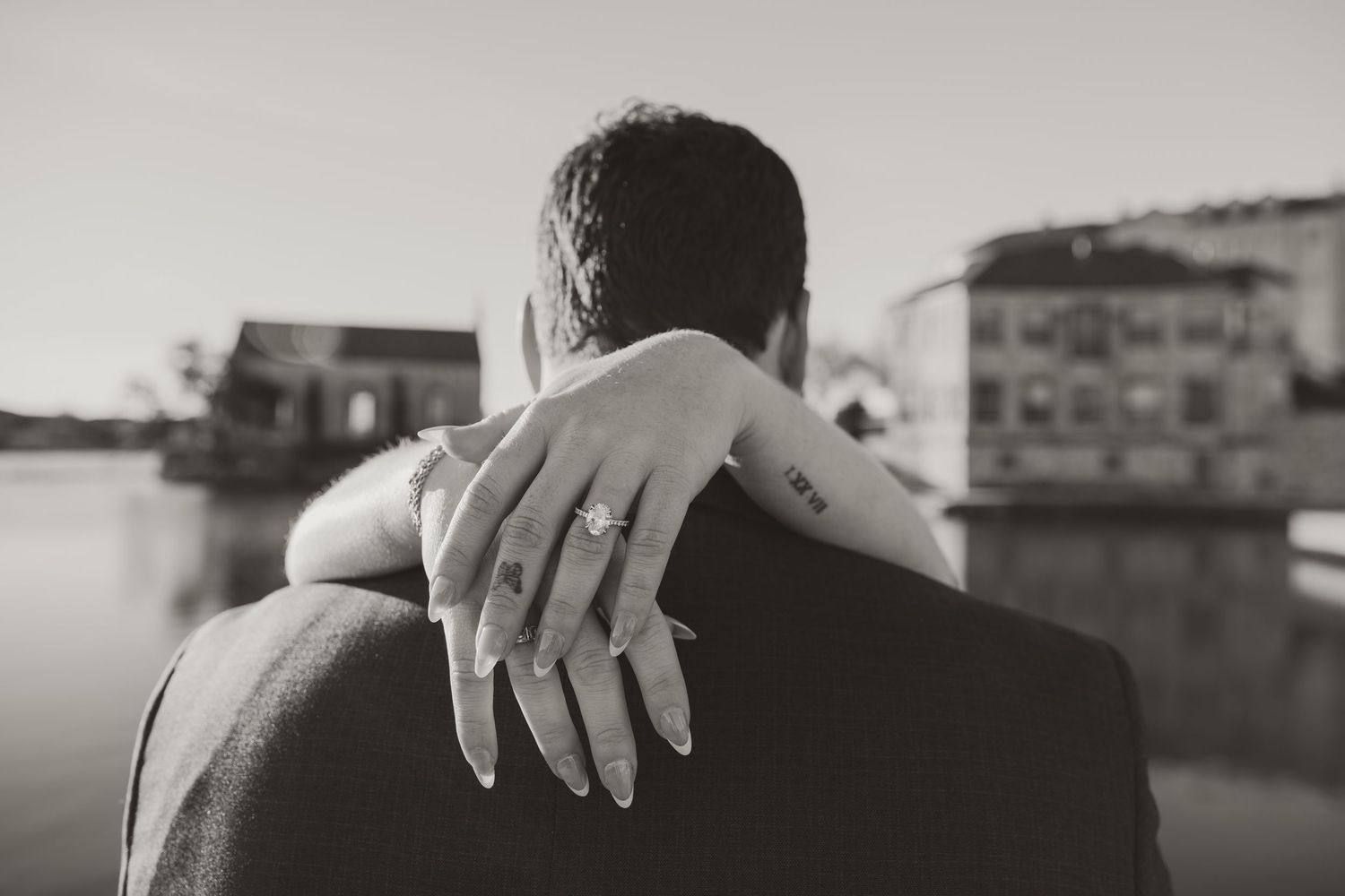 A black and white close-up of hands tenderly embracing during an intimate moment.