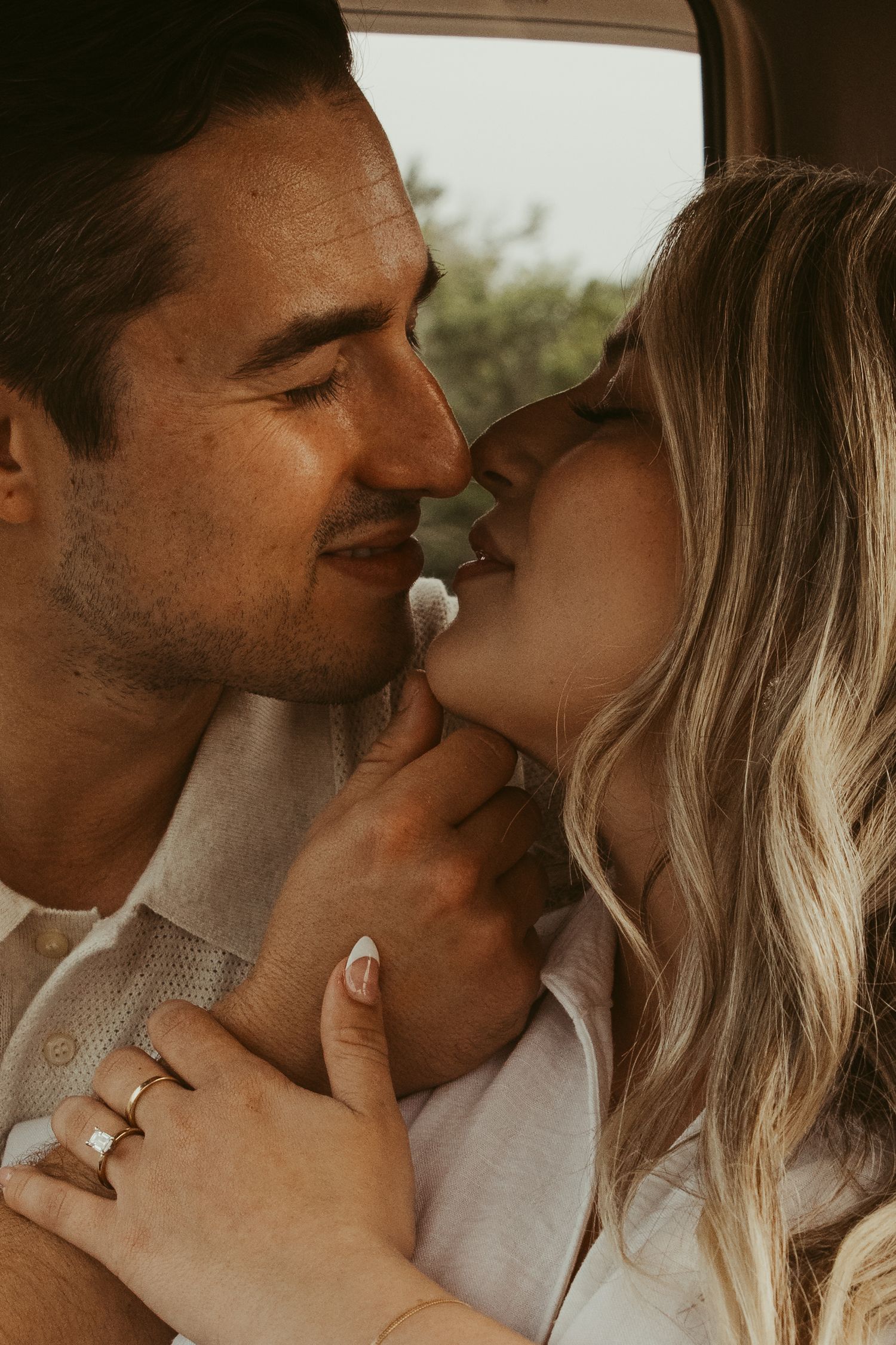 Intimate couple sharing a tender romantic moment by a window in warm lighting.