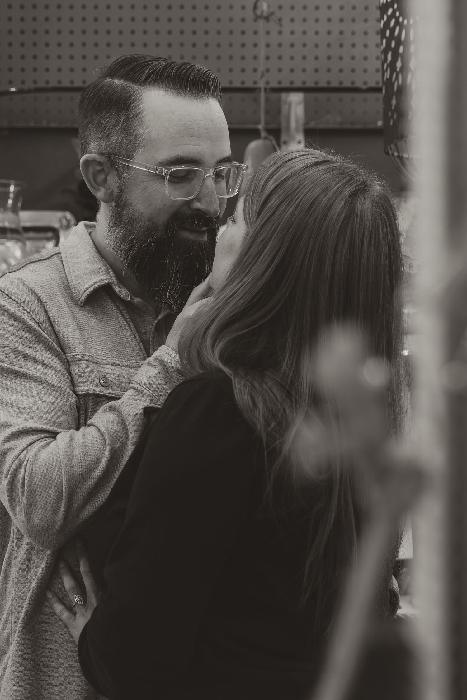 A black and white intimate moment between a bearded man in glasses and denim jacket with someone in dark clothing.