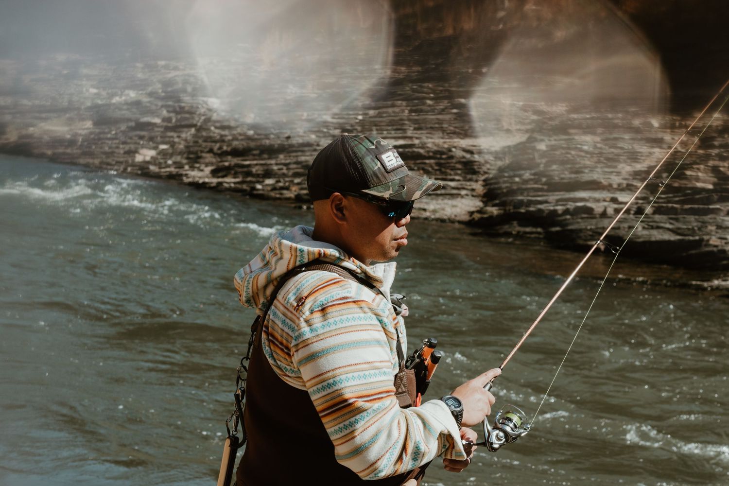 An angler fishing near rocky cliffs in misty conditions.