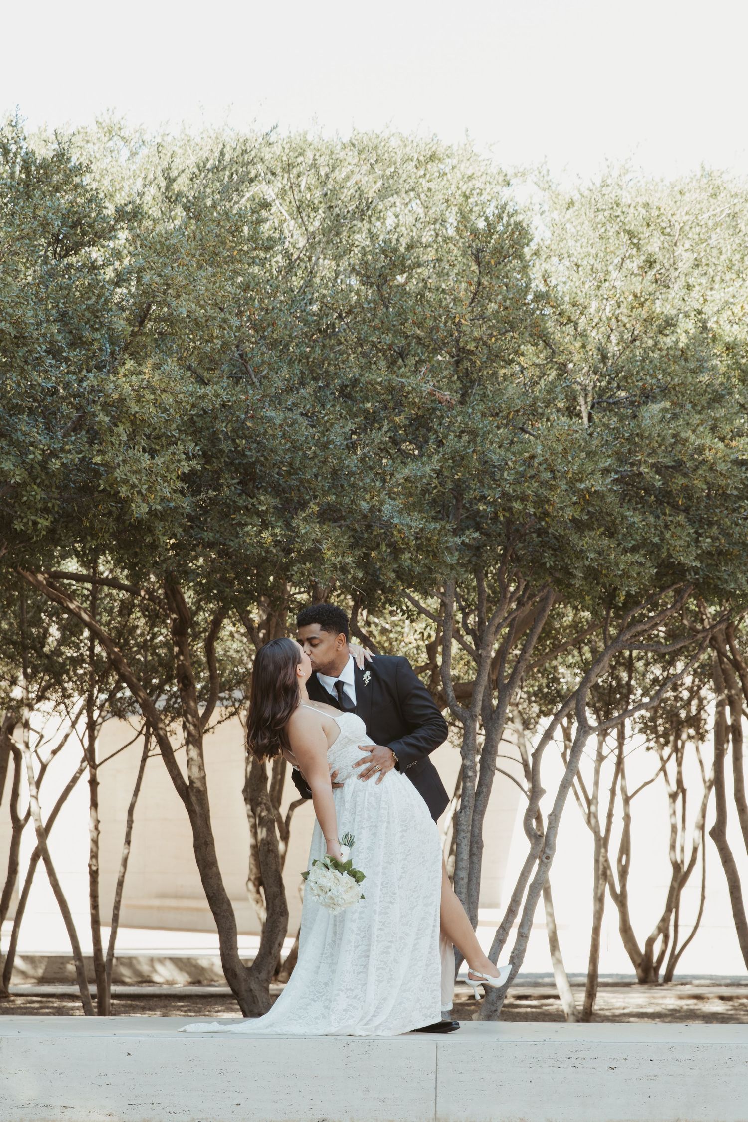 Romantic portrait among olive trees with flowing white dress and formal attire. Wedding Photographer DFW