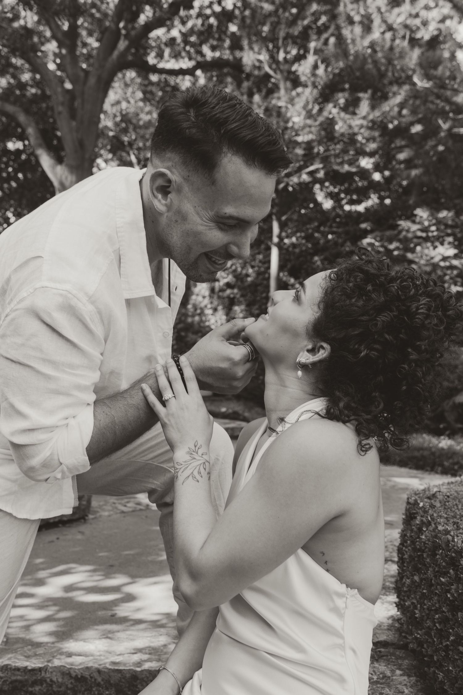 A series of romantic black and white photos showing a tender kiss between a couple in a sunlit garden.