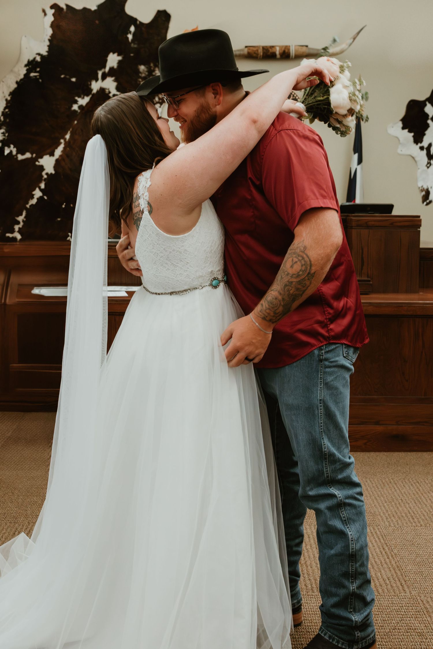 A couple shares their first kiss as newlyweds in a rustic church setting with wooden panels.