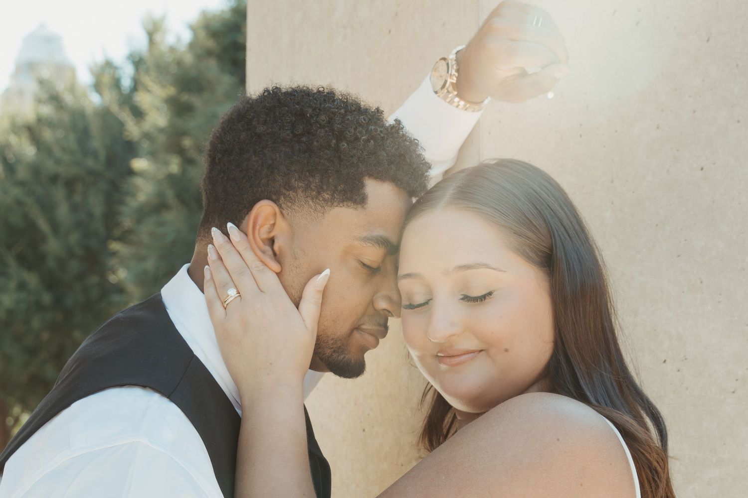 A tender wedding photoshoot moment captured outdoors against a light stone wall background. Wedding Photographer DFW