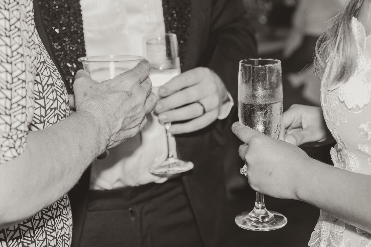 Black and white photo of wedding guests toasting with champagne glasses.