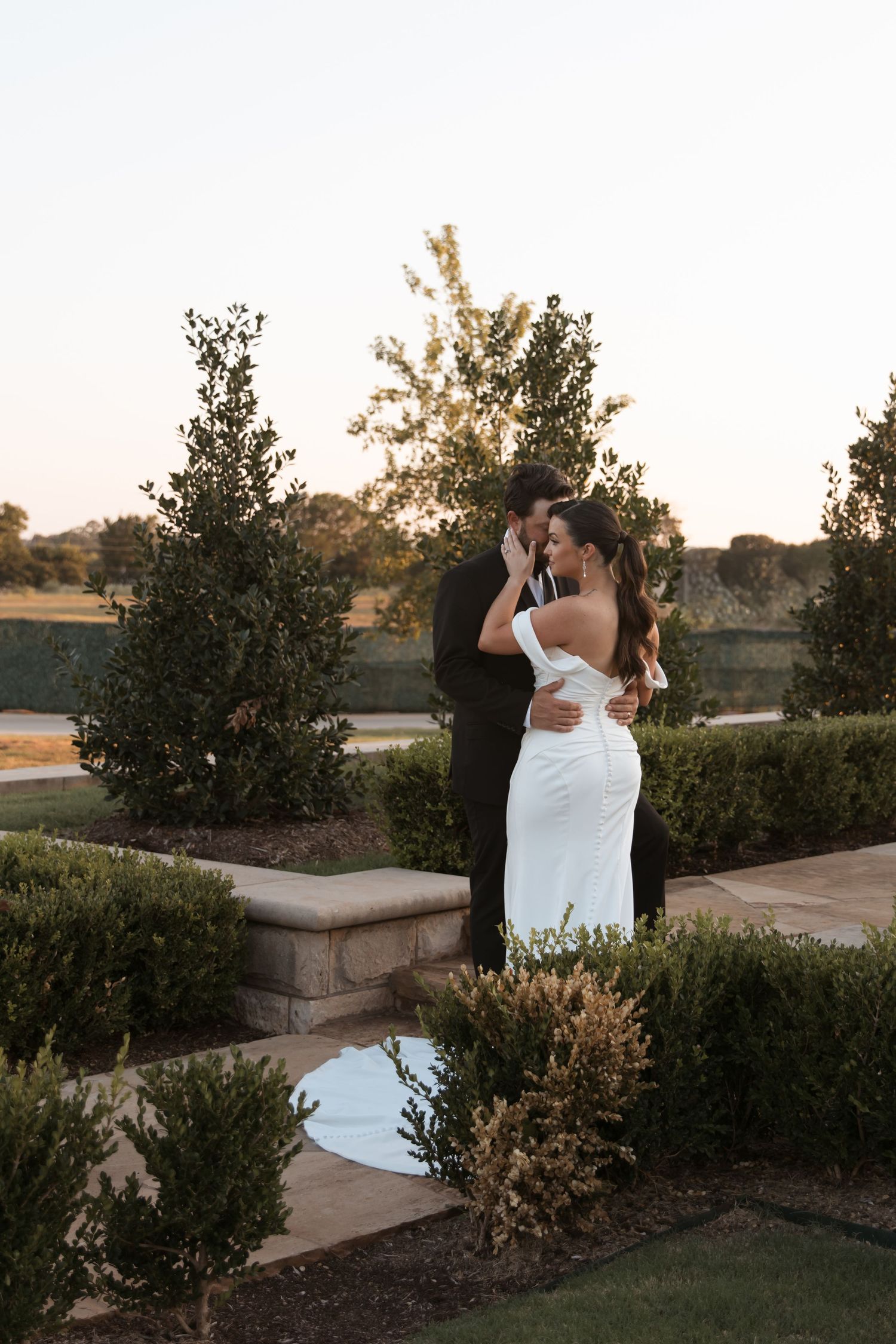 Romantic sunset garden wedding portraits captured among manicured shrubs and stone walls.