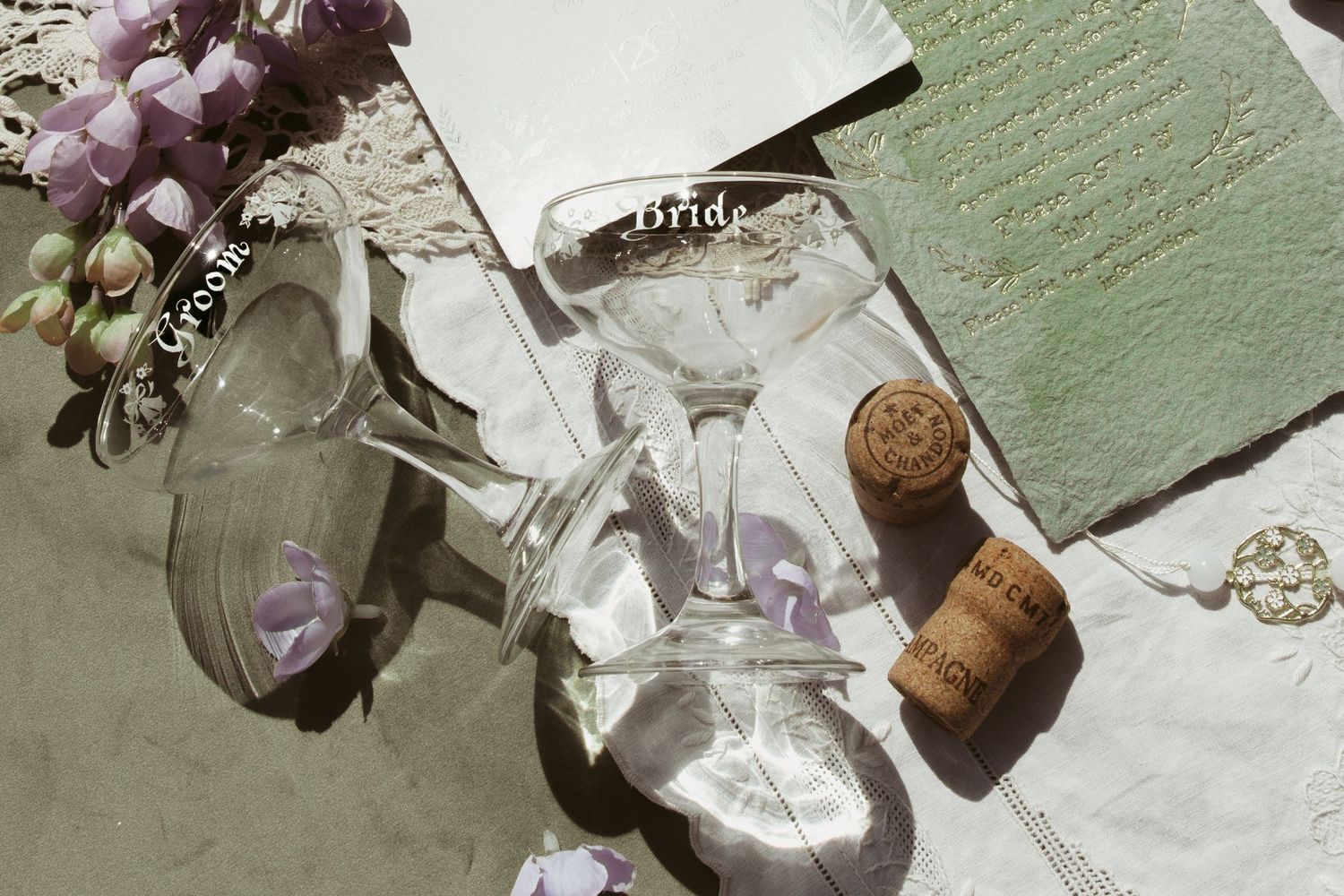 Purple dried flowers and a cork stopper arranged with vintage papers and strings on a textured white surface.