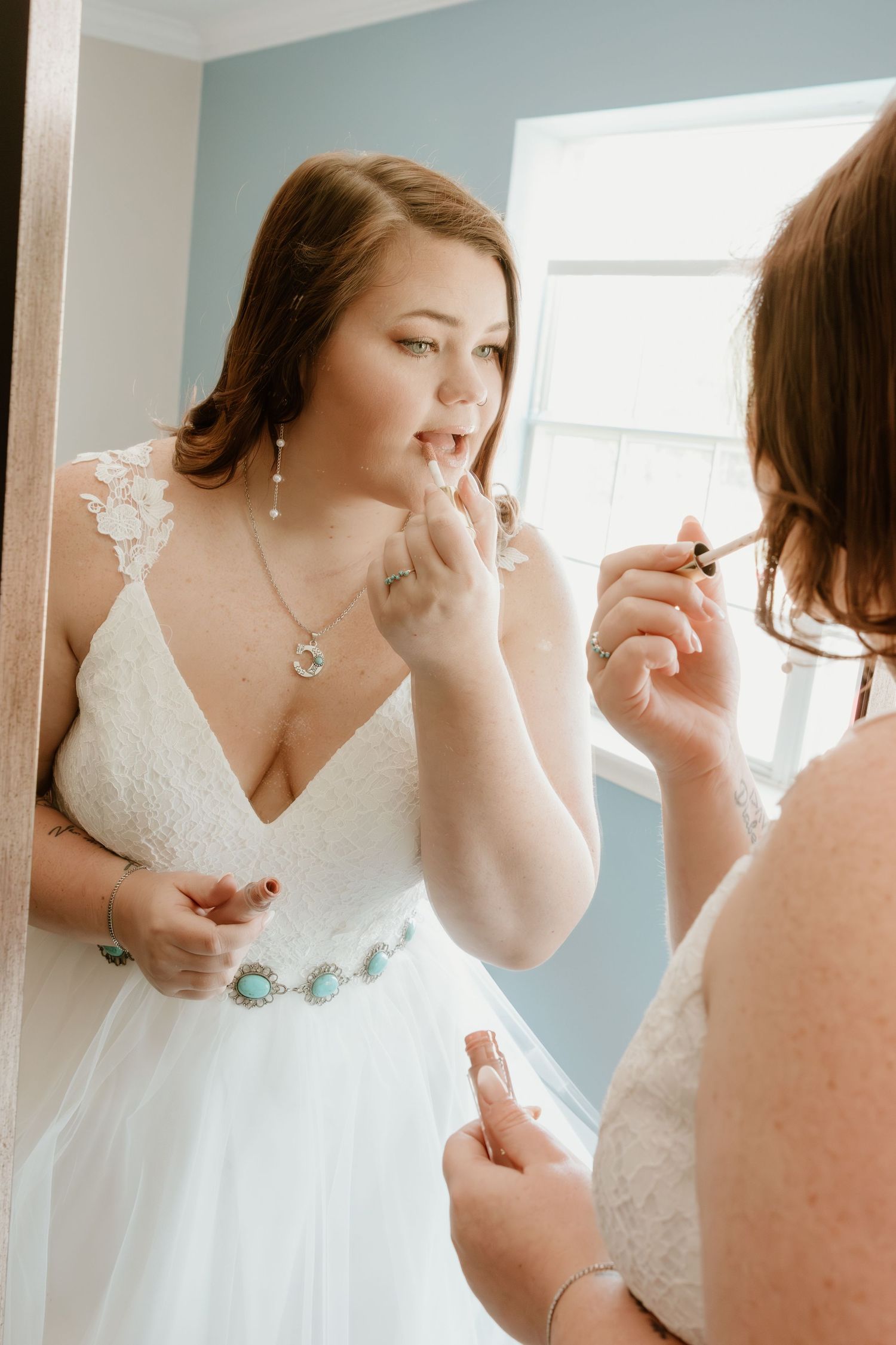 Wedding dress preparation scene with white lace dress and natural window lighting.