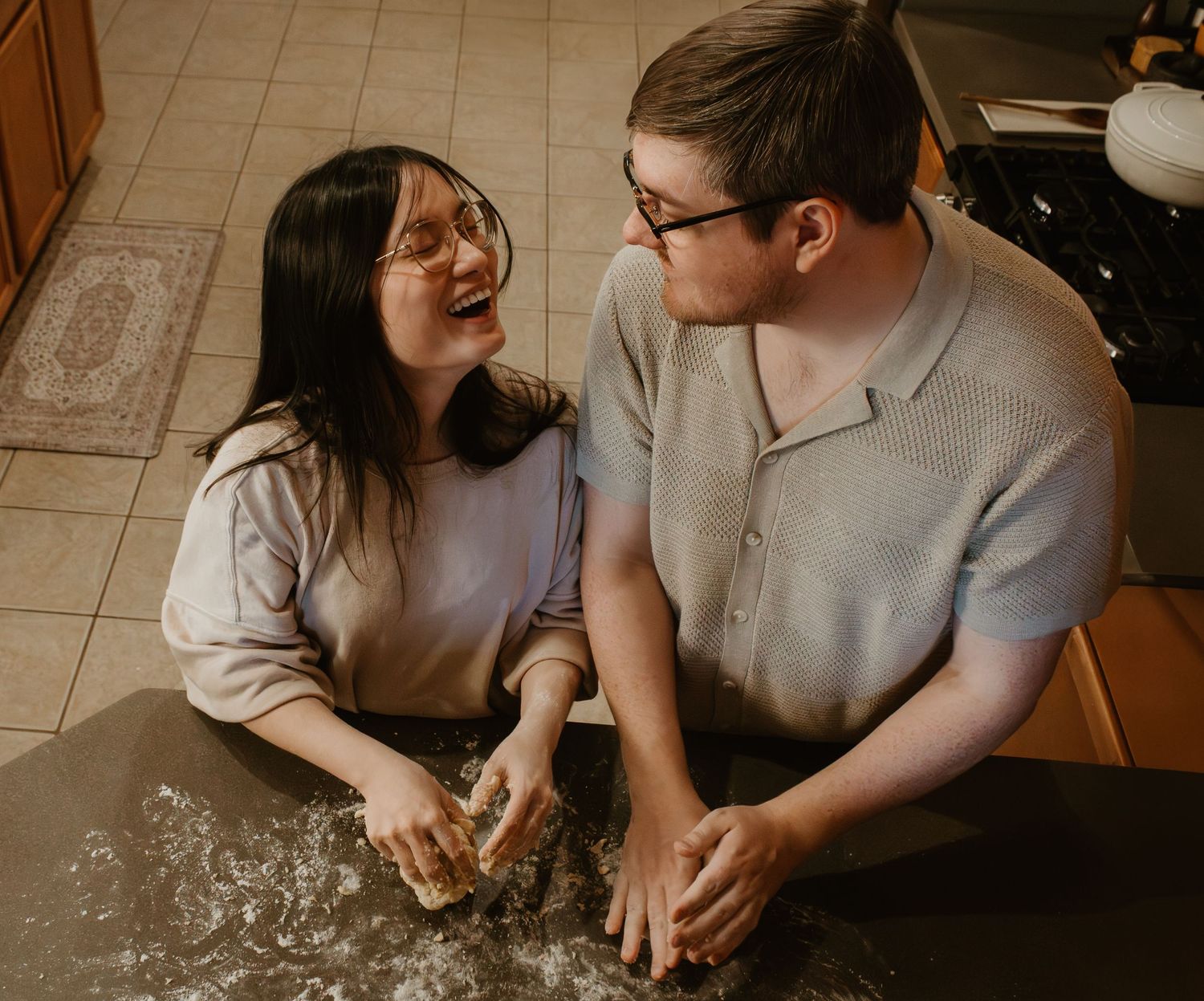 A joyful cooking moment between a couple making homemade pasta in their kitchen.
