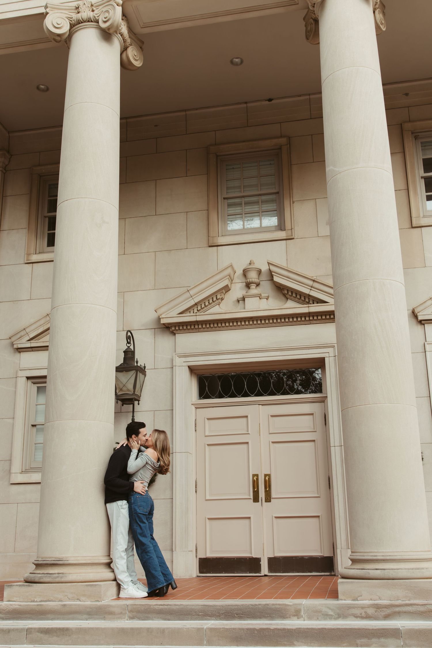 Romantic couple shares tender moments under elegant white columns of a grand building entrance engagement photos Fort Worth