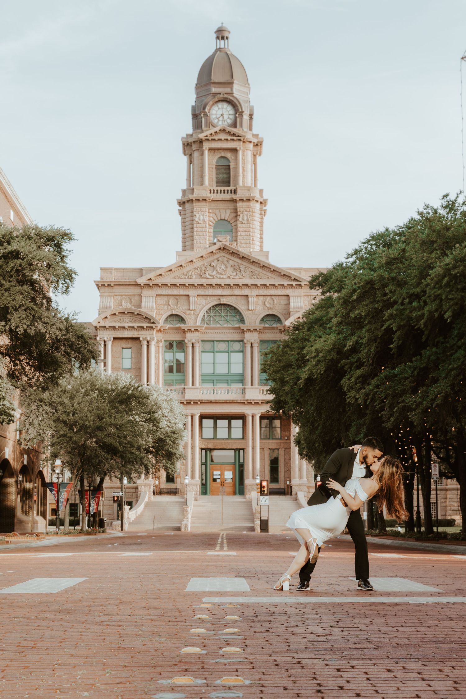 A romantic couple dances outside the historic Tarrant County Courthouse with its grand clock tower in Fort Worth, Texas.