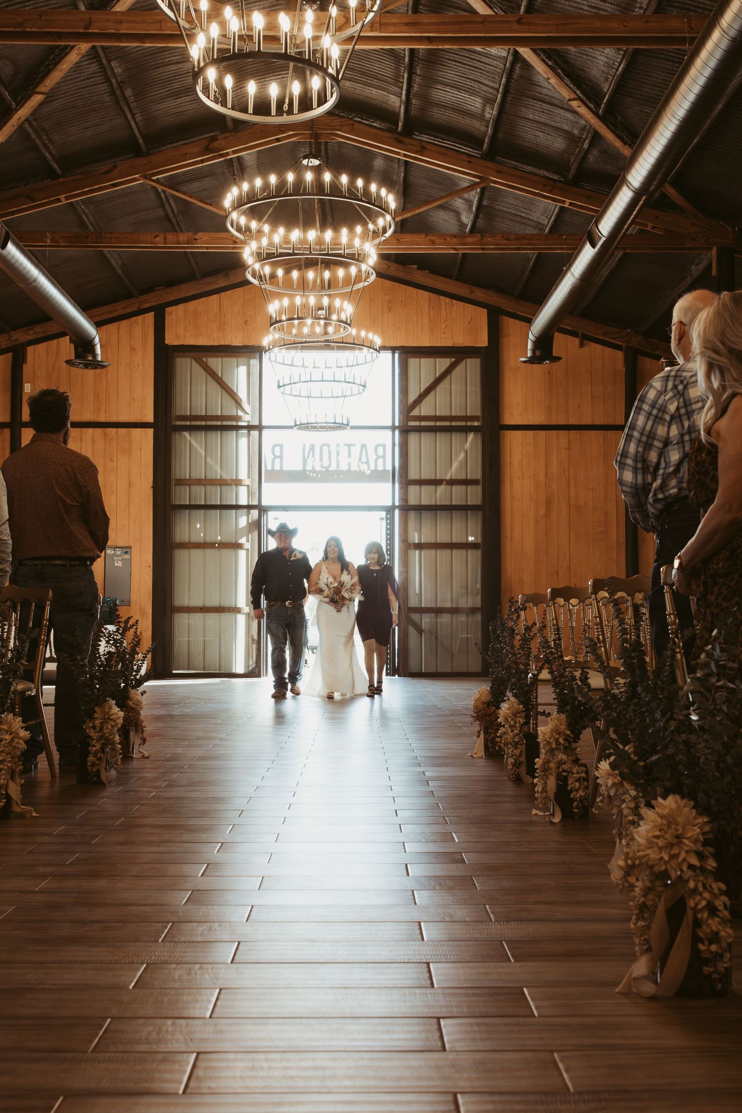 Rustic barn wedding venue with chandelier lighting and wooden beams. Wedding photographer DFW