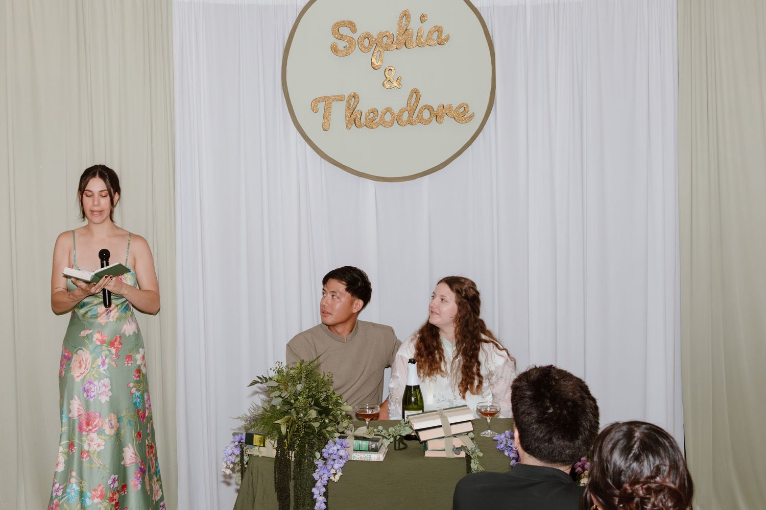 Wedding reception setup with decorative sign and floral centerpieces.
