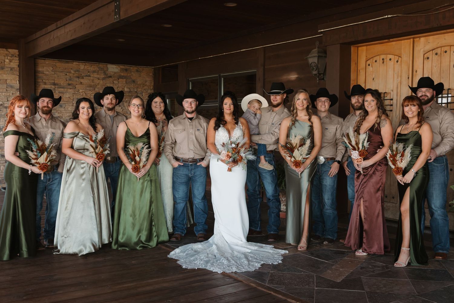 Wedding party members lined up against rustic wooden wall at reception venue.