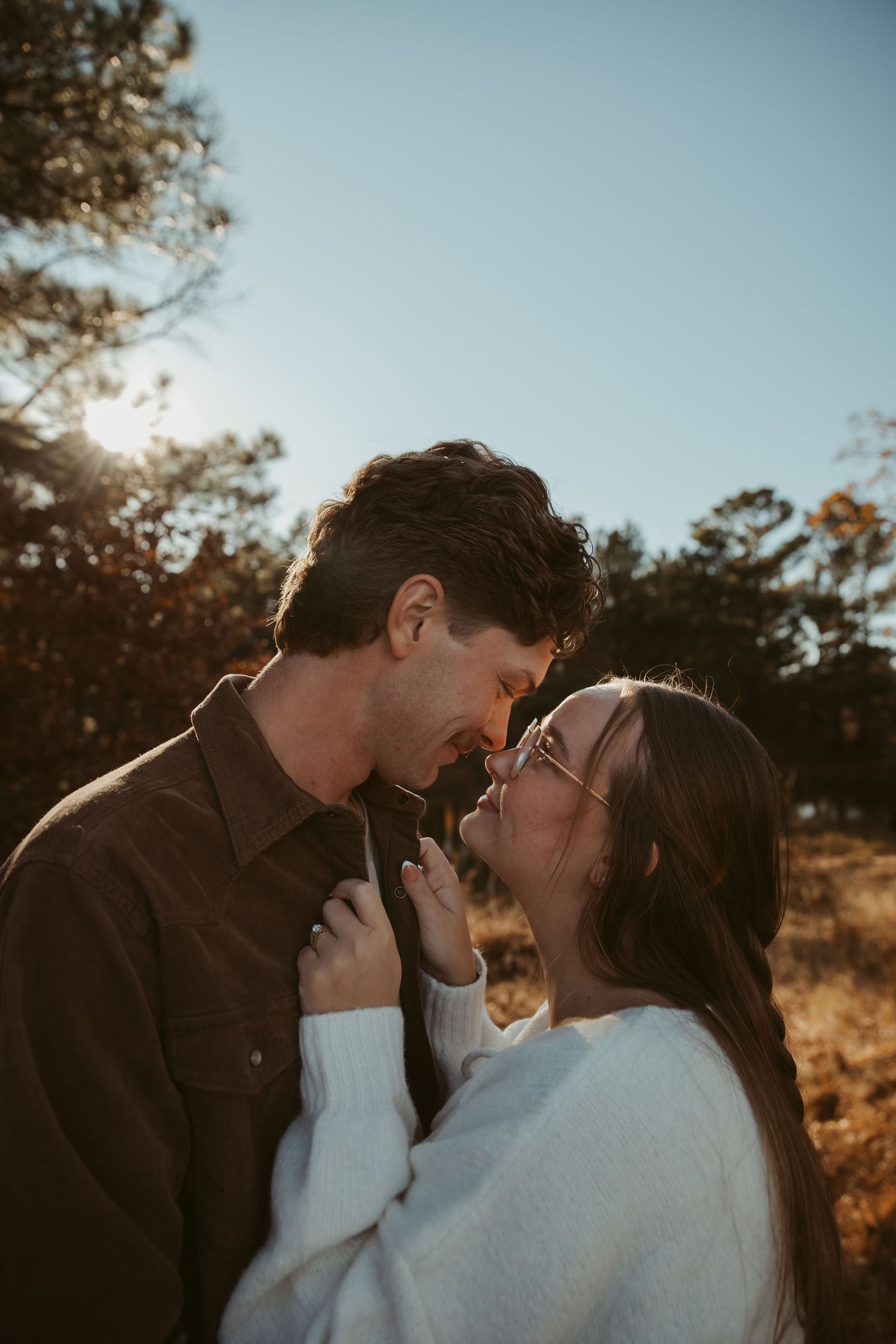 A romantic couple shares an intimate moment in warm sunlight during an outdoor photoshoot. engagement photos DFW