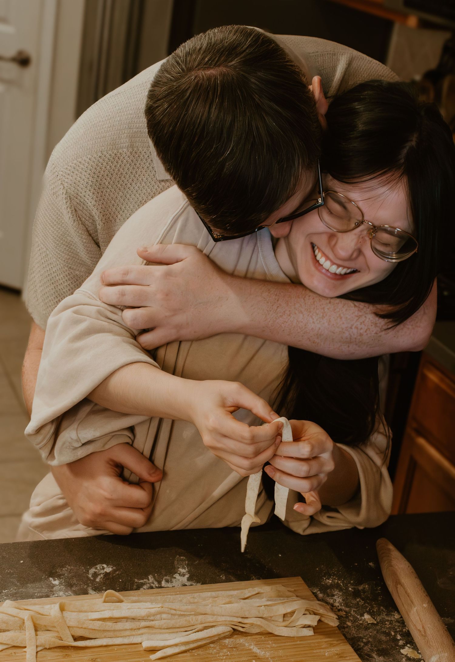 A tender embrace shared while making homemade pasta in the kitchen.