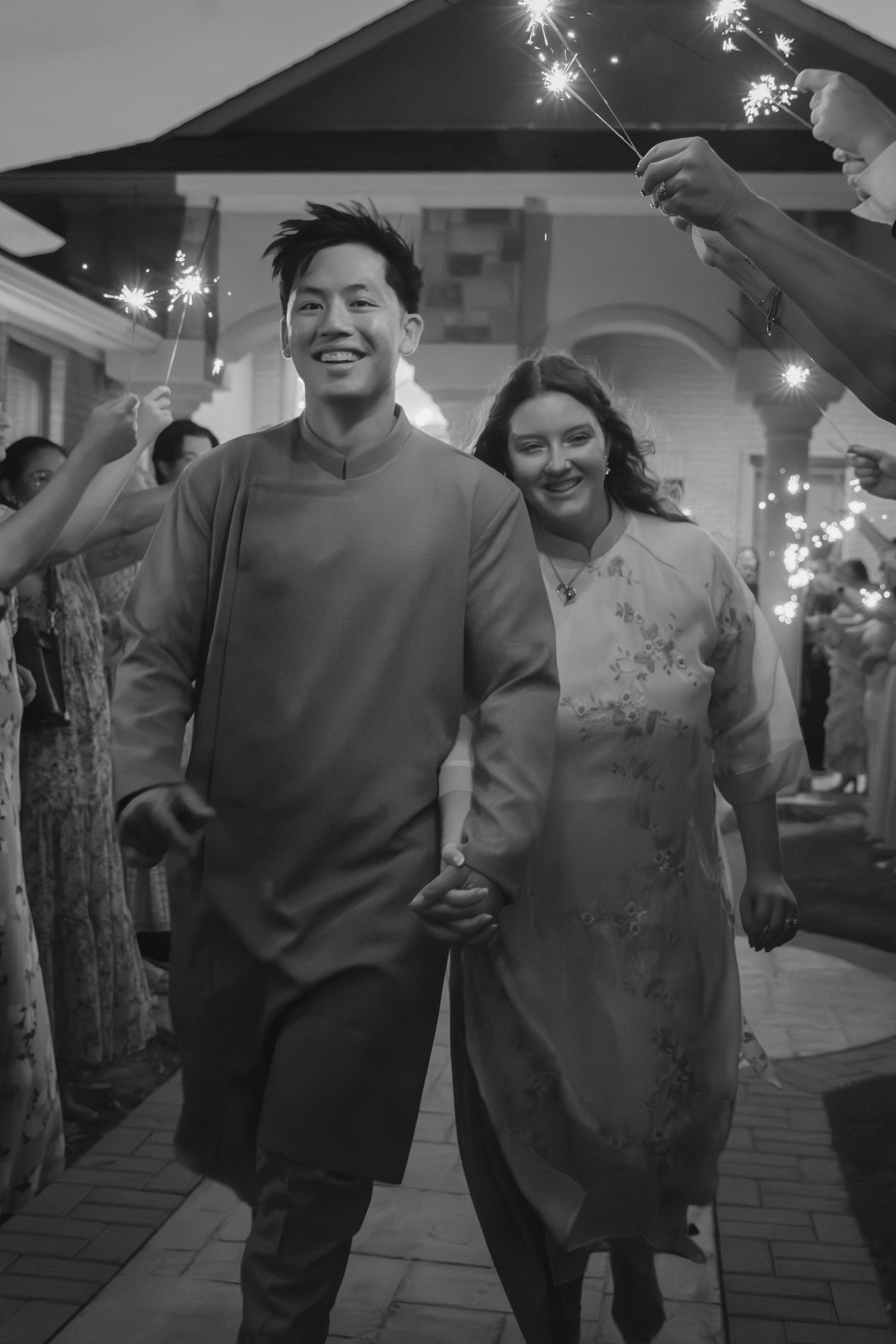 Couple runs through sparkler exit at nighttime wedding celebration.