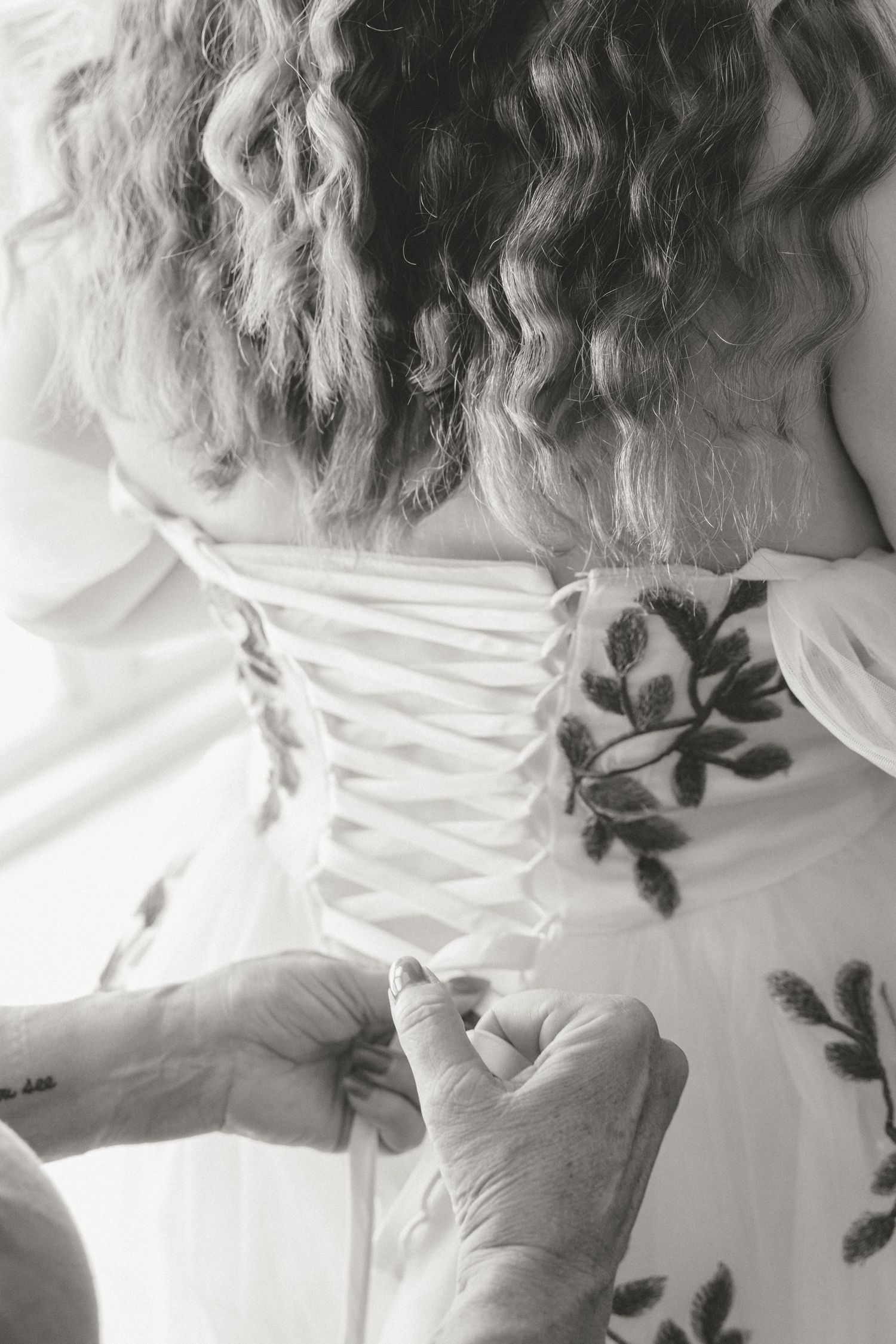 A series of black and white photos showing the back details of a white corset dress with floral embellishments.