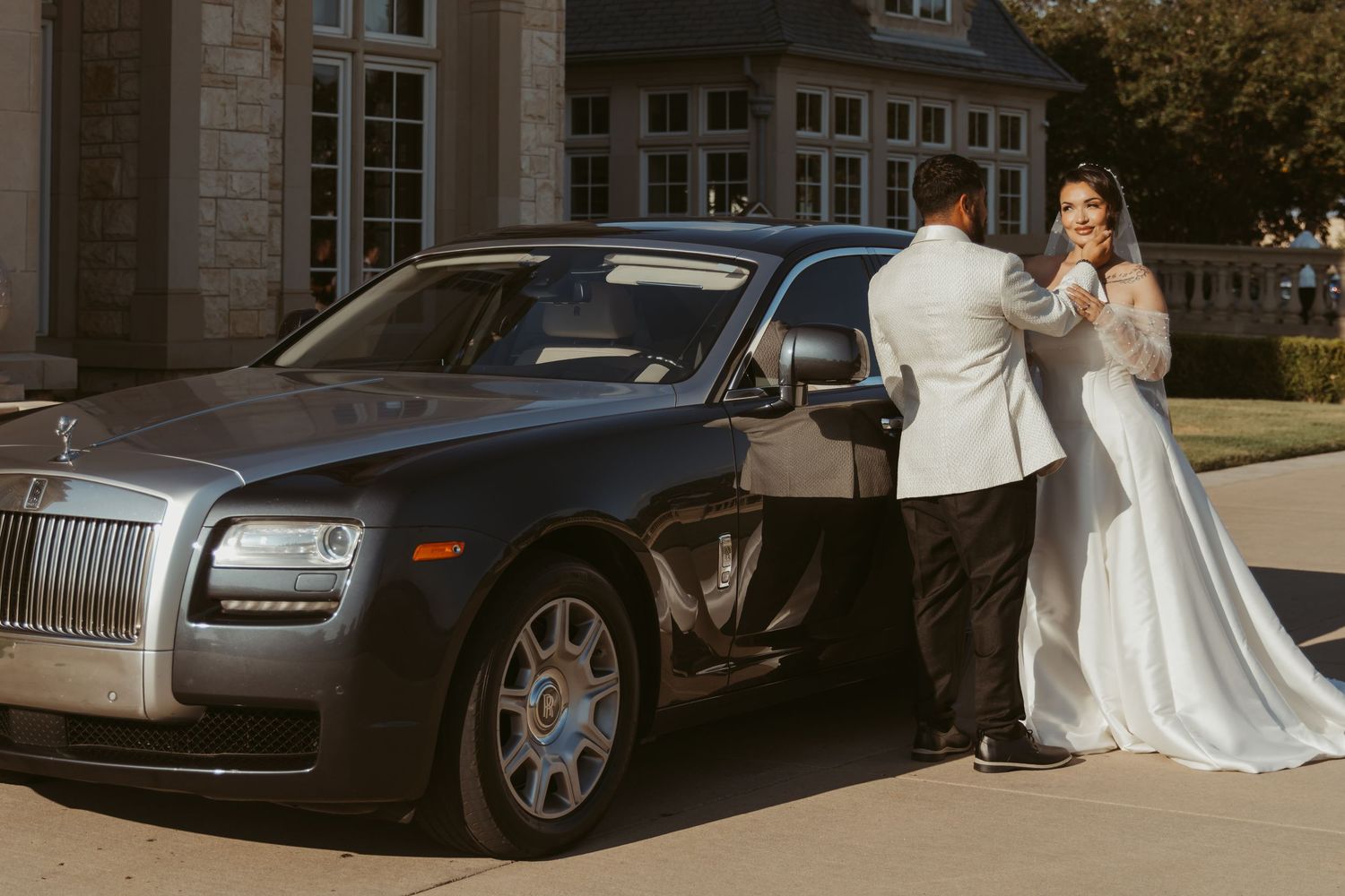 A line of luxury Rolls-Royce vehicles parked outside an elegant stone building.