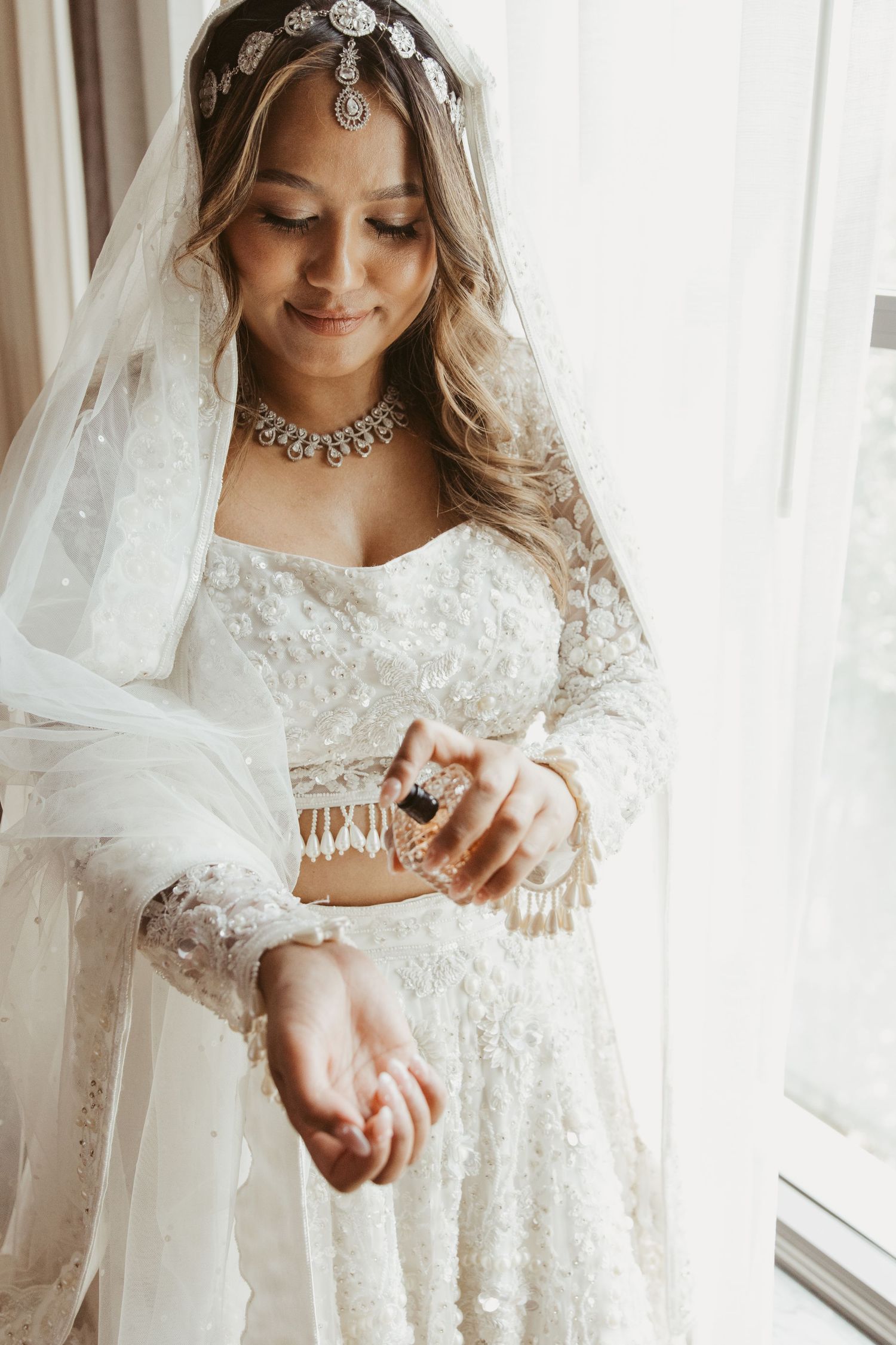 A close-up sequence of a bride in an elegant lace wedding gown and veil preparing for her special day.