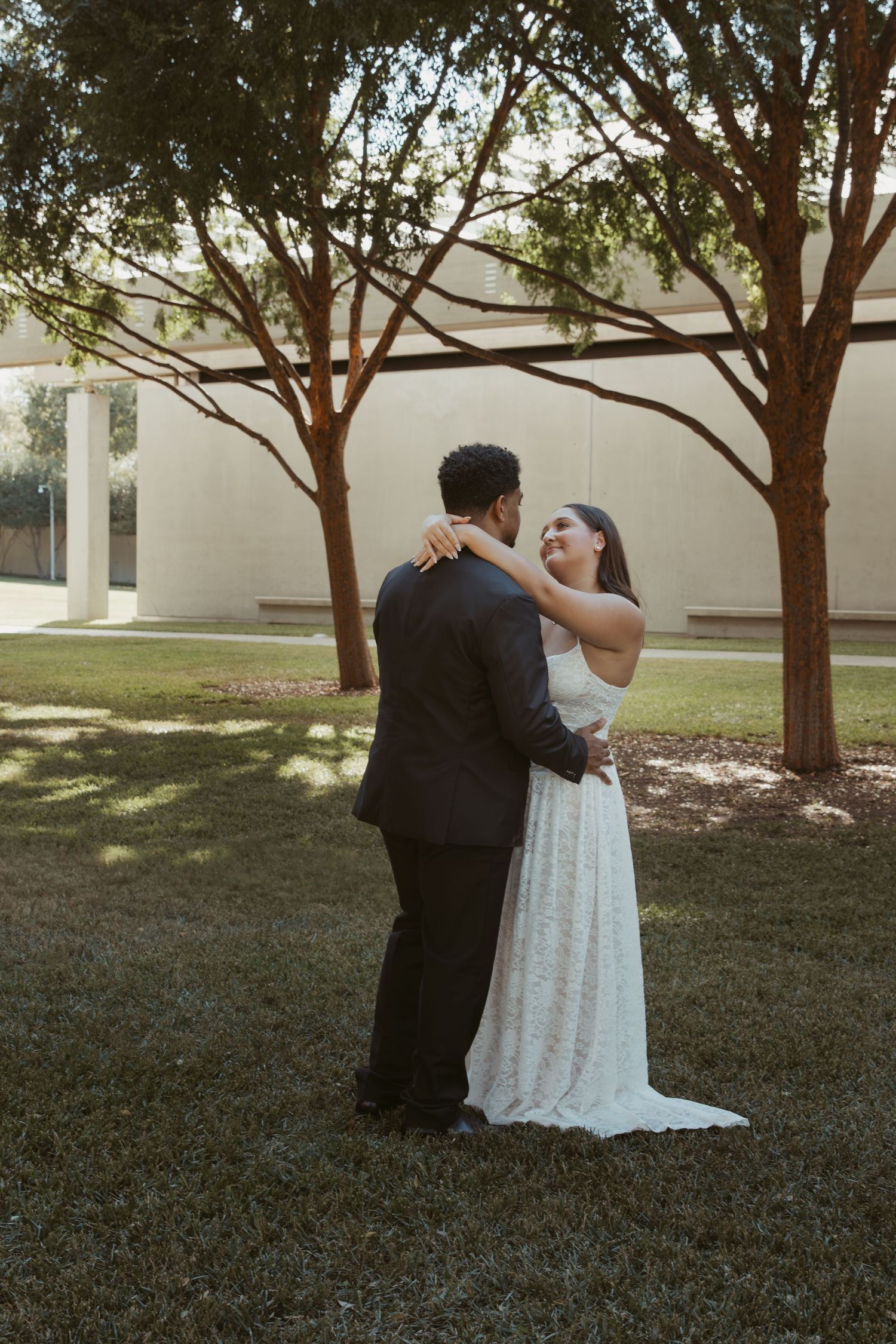 Romantic moment captured between couple in formal wear under tree-lined path. Wedding Photographer DFW