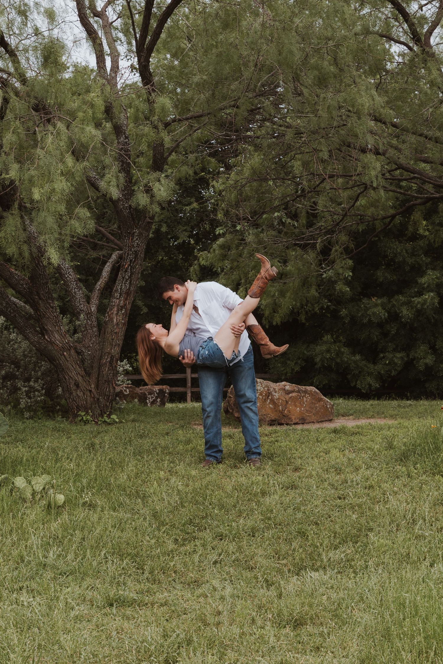A romantic outdoor dance move being performed on grassy lawn with lush trees in the background.
