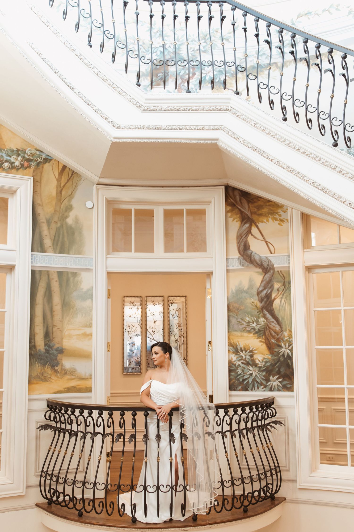 Elegant indoor balcony with ornate iron railings and painted wall murals in a luxurious wedding venue.