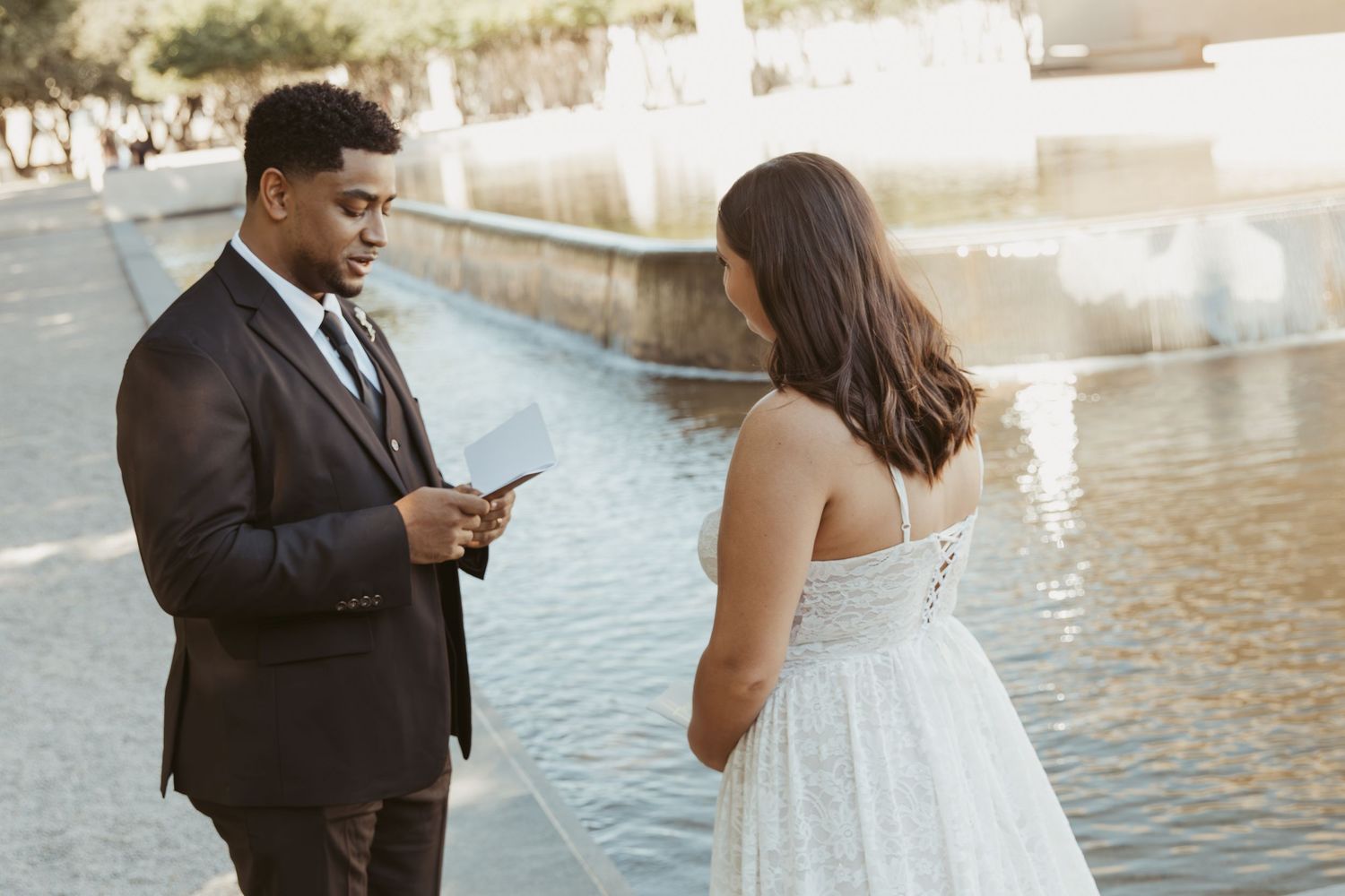 A couple shares an intimate moment together by a serene waterfront setting during a formal photoshoot. Wedding Photographer DFW
