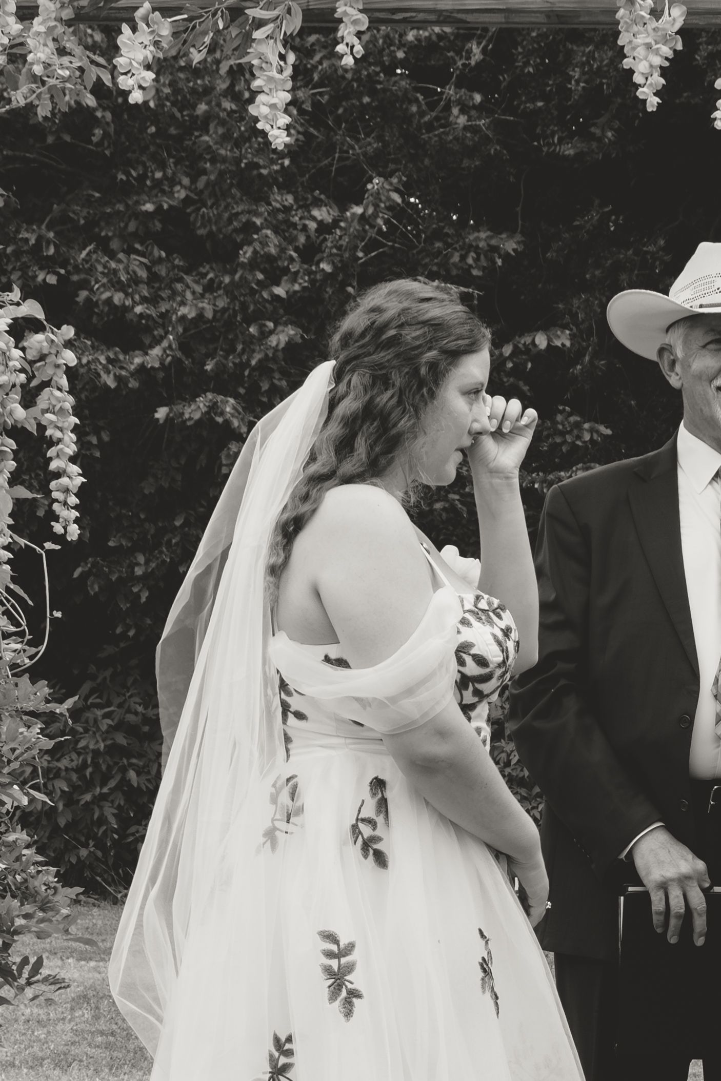 Candid moments captured during an outdoor wedding ceremony with hanging floral decorations.