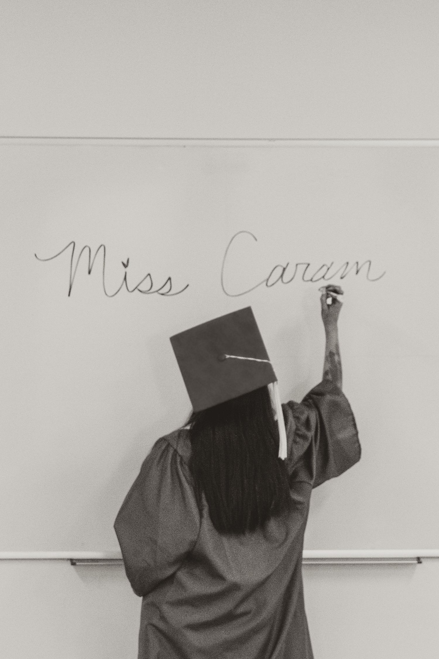 Graduate in cap and gown writing 