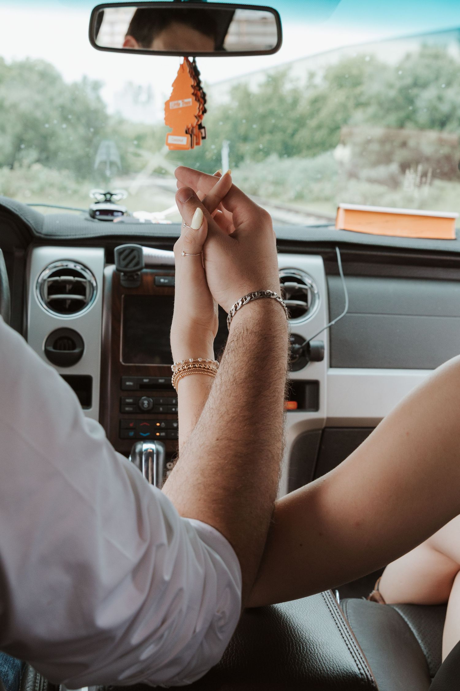 A series of five connected photos show fingers playing with a tiny orange rubber duck toy on a car dashboard.