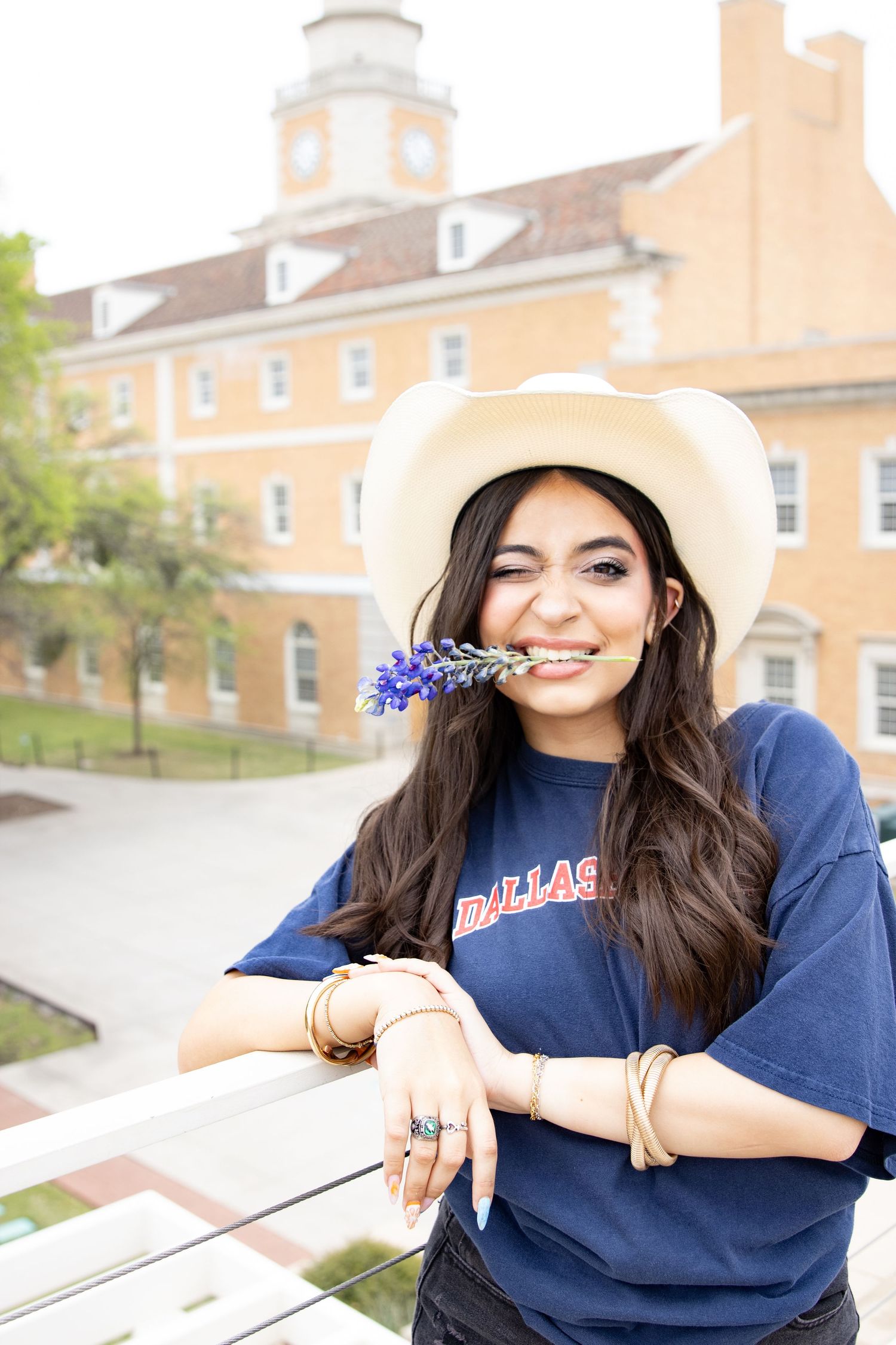 Candid moment with purple flowers and white cowboy hat against collegiate architecture.