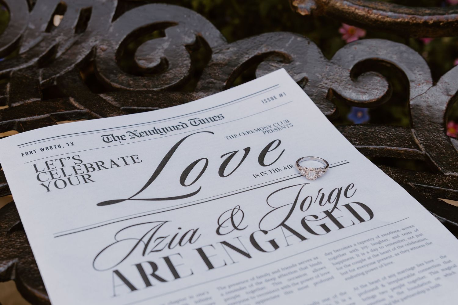 Elegant wedding invitations with calligraphy text displayed on a dark wooden surface with scattered greenery.
