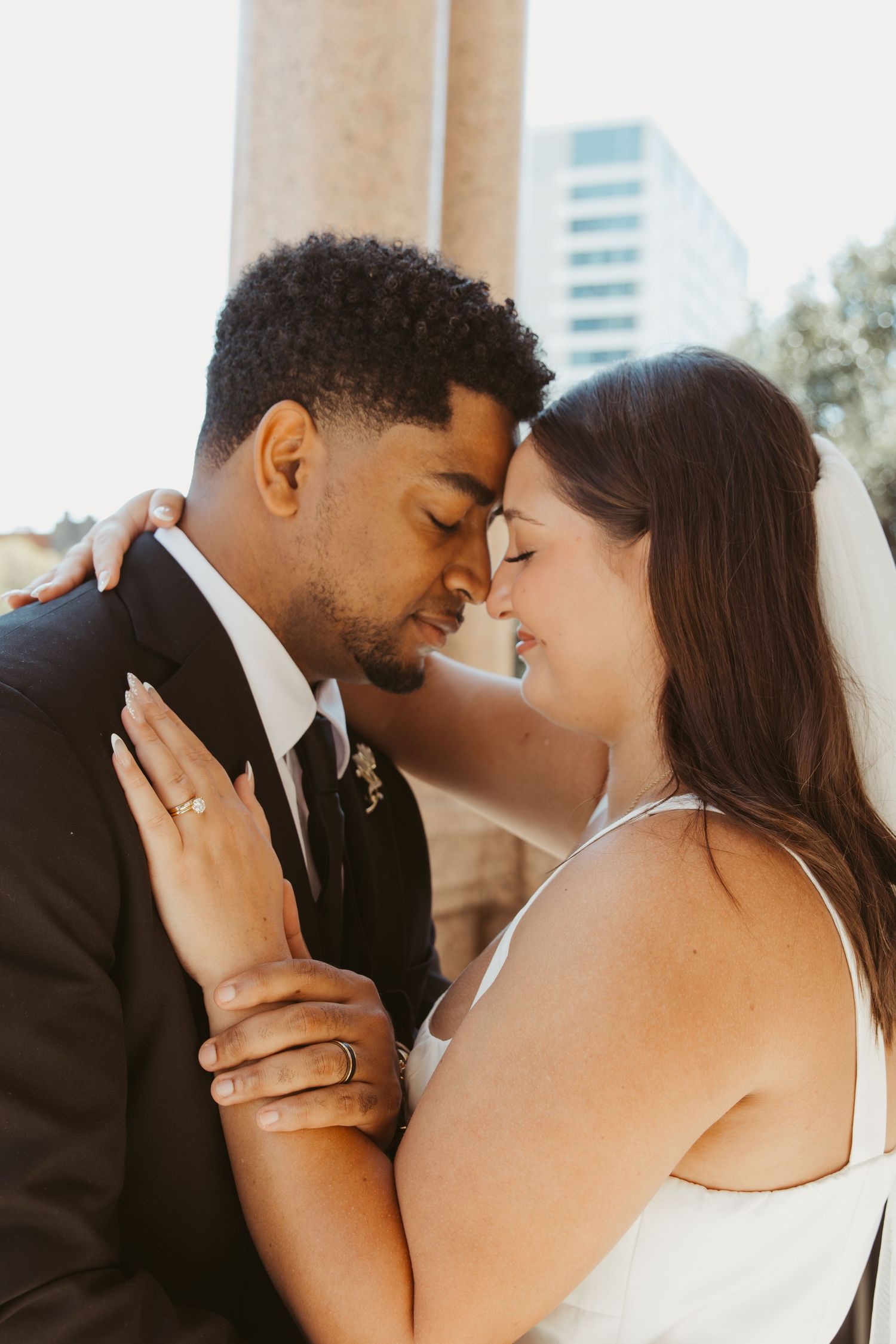 A couple shares an intimate moment in front of a light-filled window. Wedding Photographer DFW