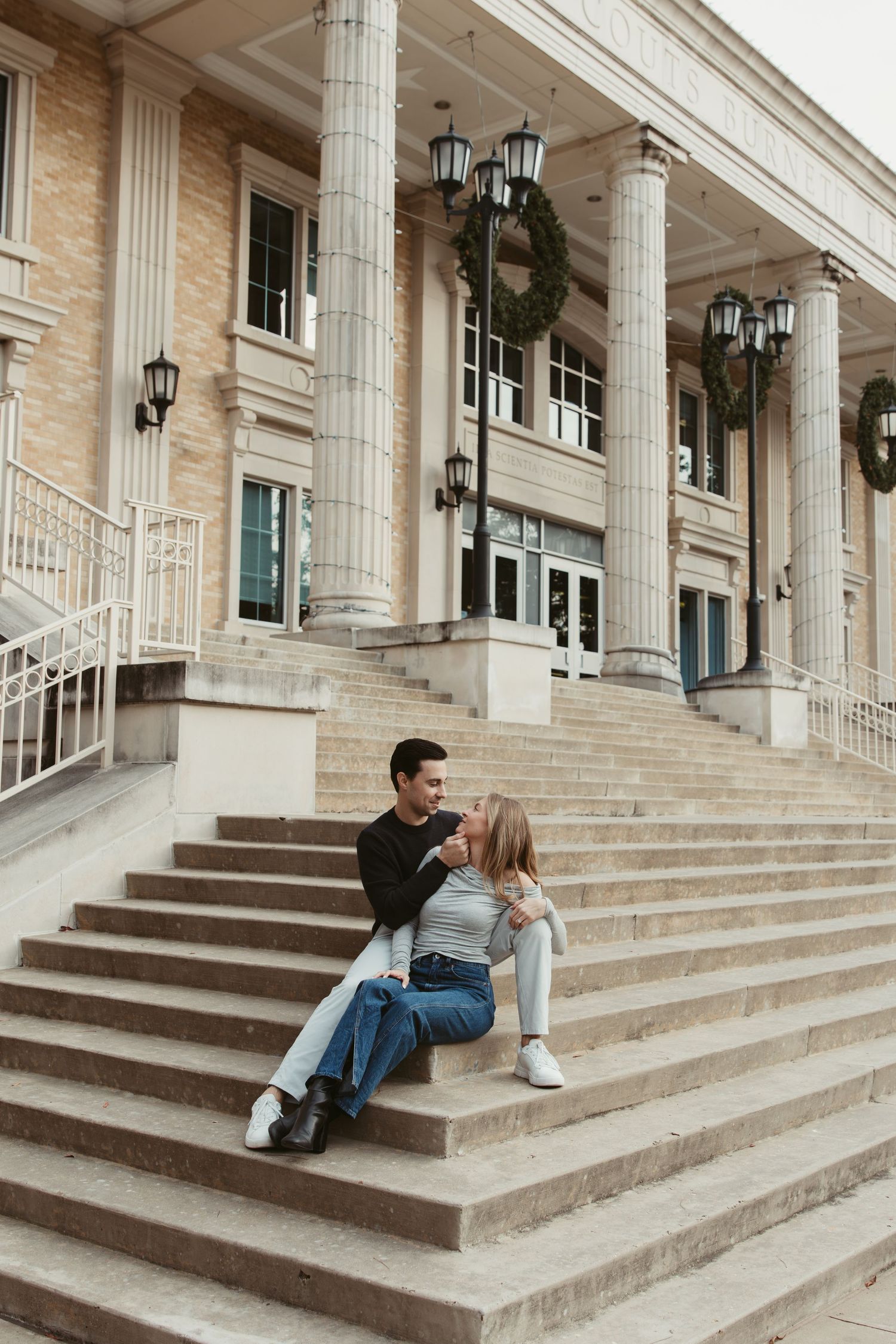 Couple sitting and talking on grand stone steps of a historic building with white columns and lanterns.