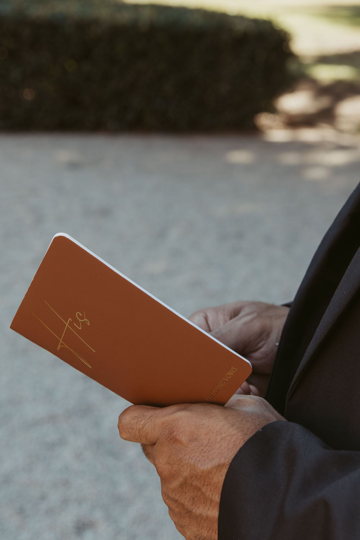 Close-up shot of hands holding a brown leather document or card. Wedding Photographer DFW