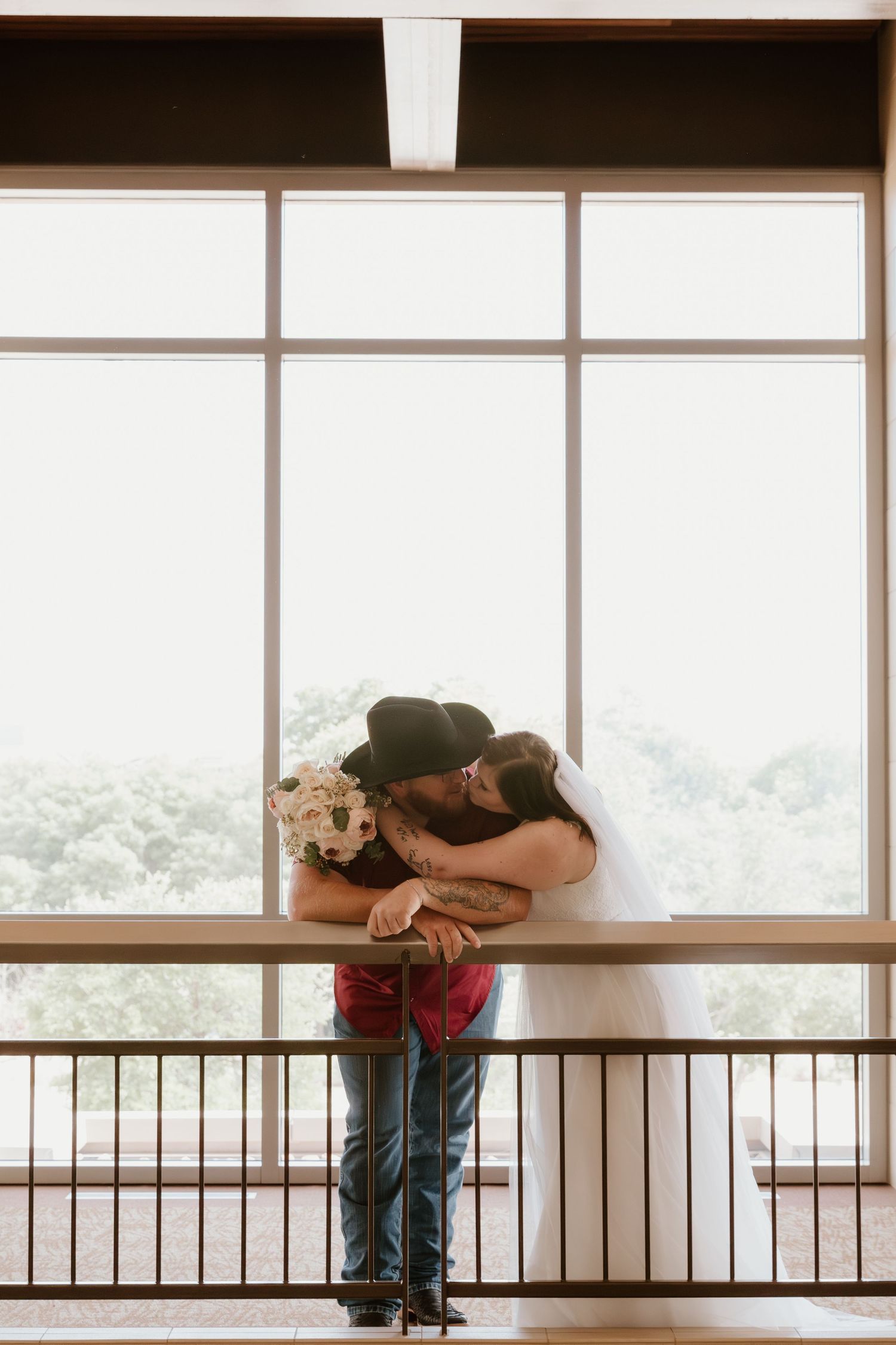 Romantic couple embracing by large window with scenic view.