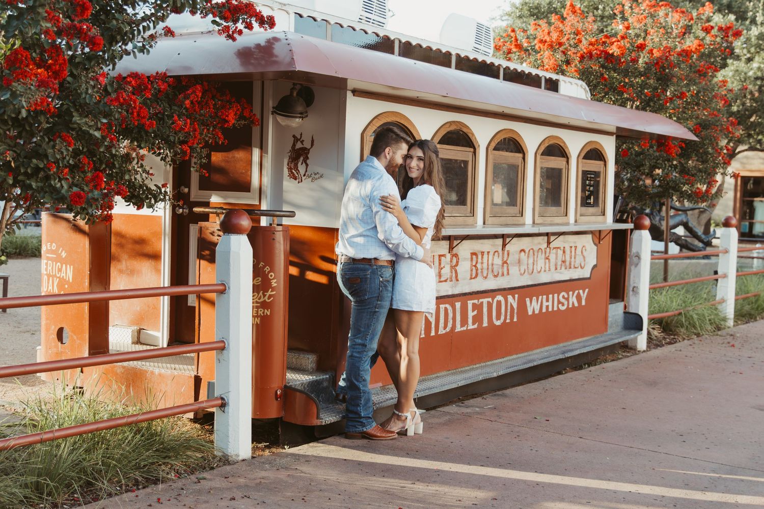 A row of train cars with red autumn foliage and vintage signage along a scenic railway platform.