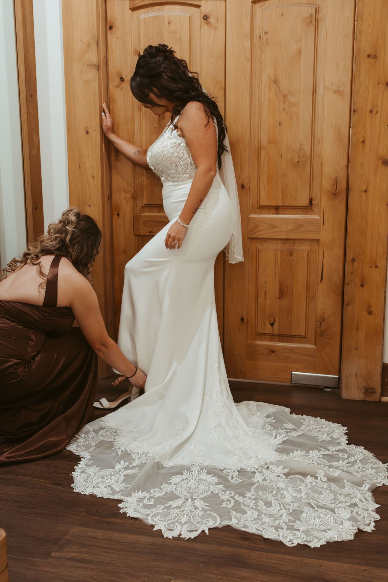 A white lace wedding dress with an elegant train displayed on a wooden floor. Wedding photographer DFW