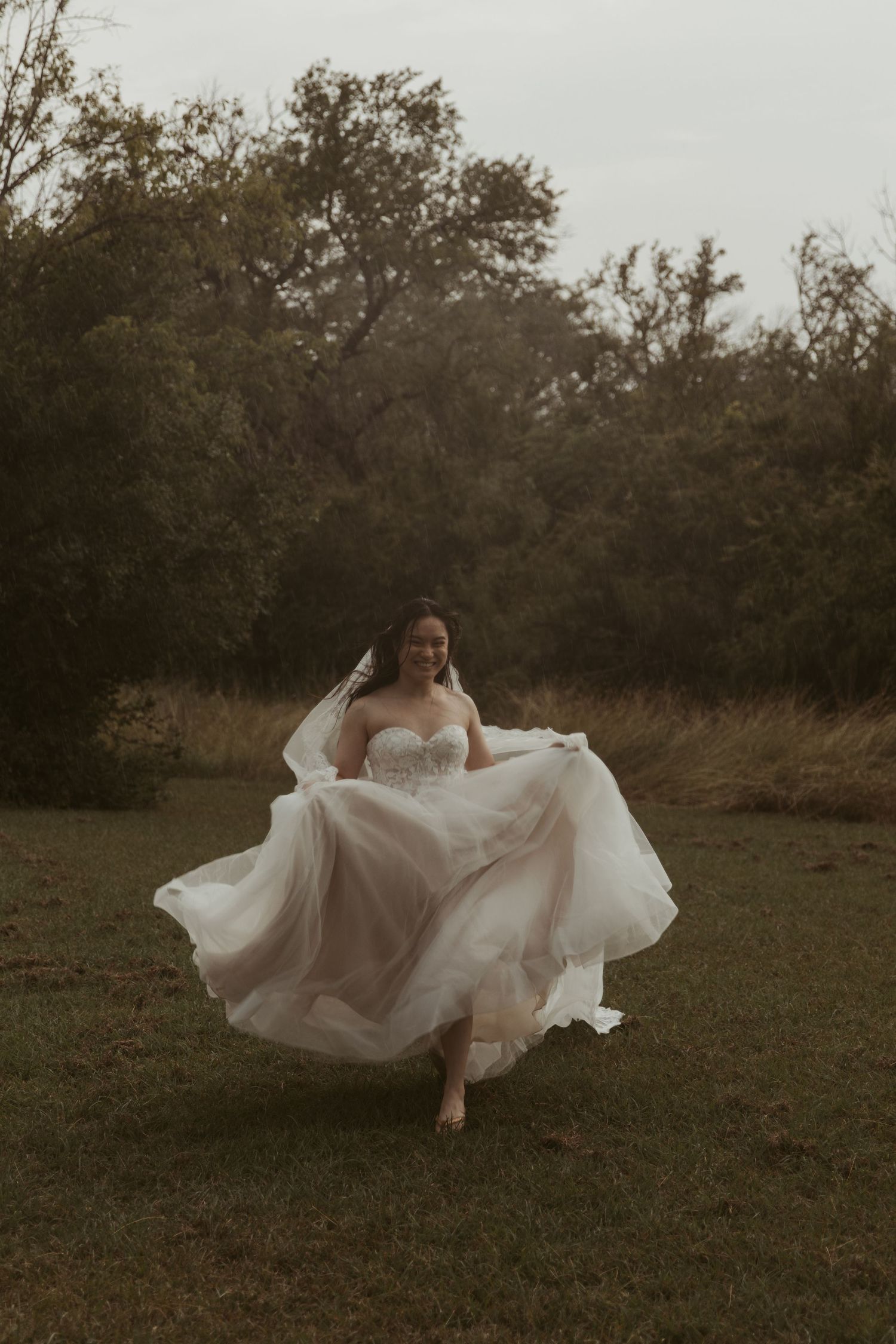 A flowing white wedding dress twirls gracefully in motion across a rustic outdoor field at dusk.