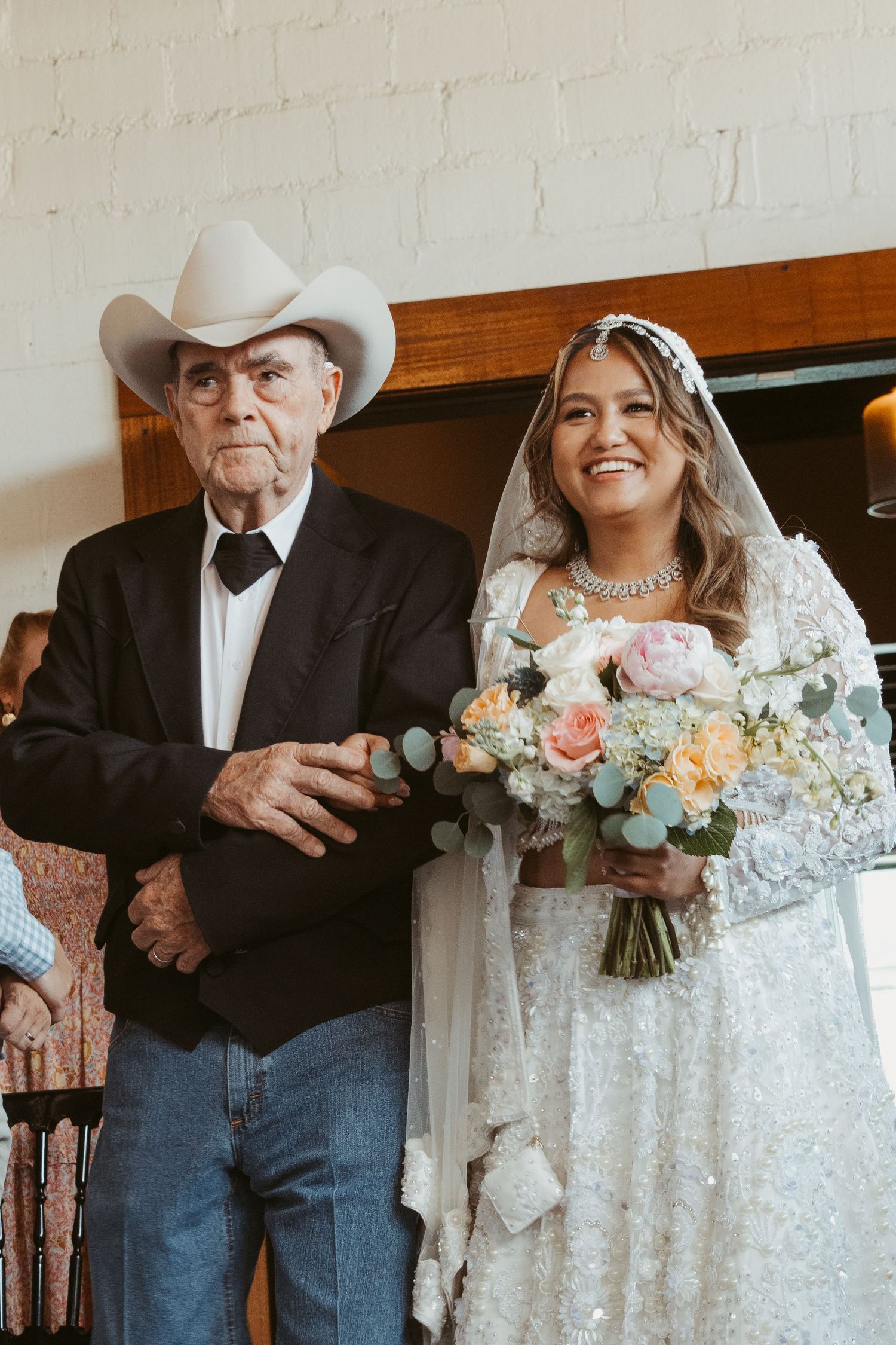 Wedding ceremony moment with attendees standing under an arch with florals and white decor.