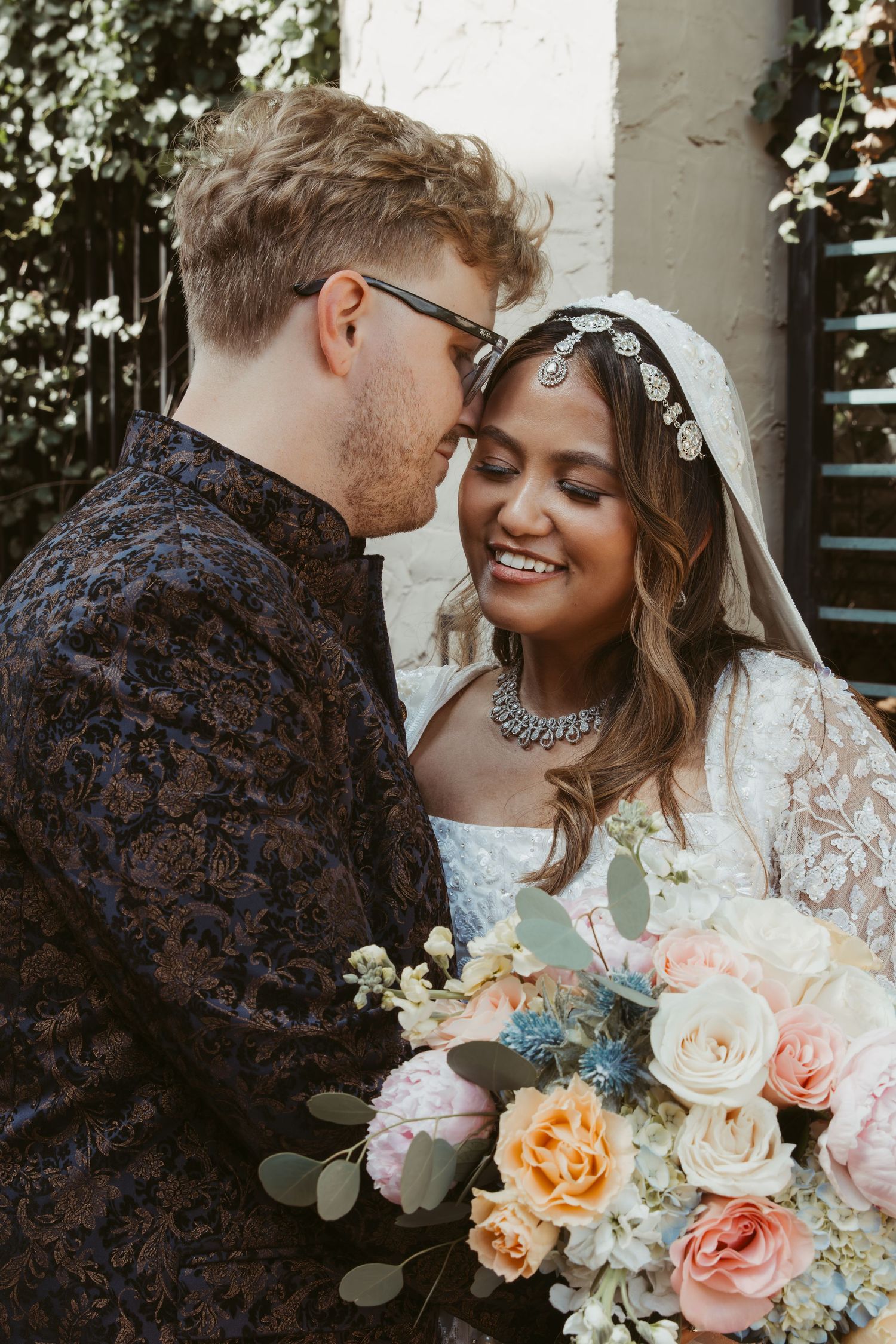 A romantic wedding portrait of a couple sharing an intimate moment with peach and white roses.