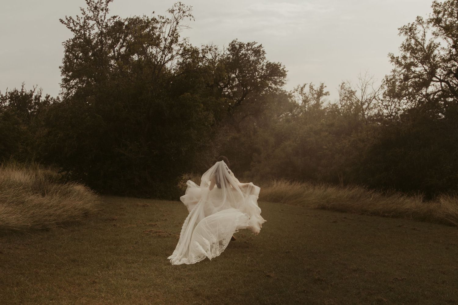 A dreamy sepia-toned photo series shows a flowing white dress moving through a natural outdoor setting at sunset.