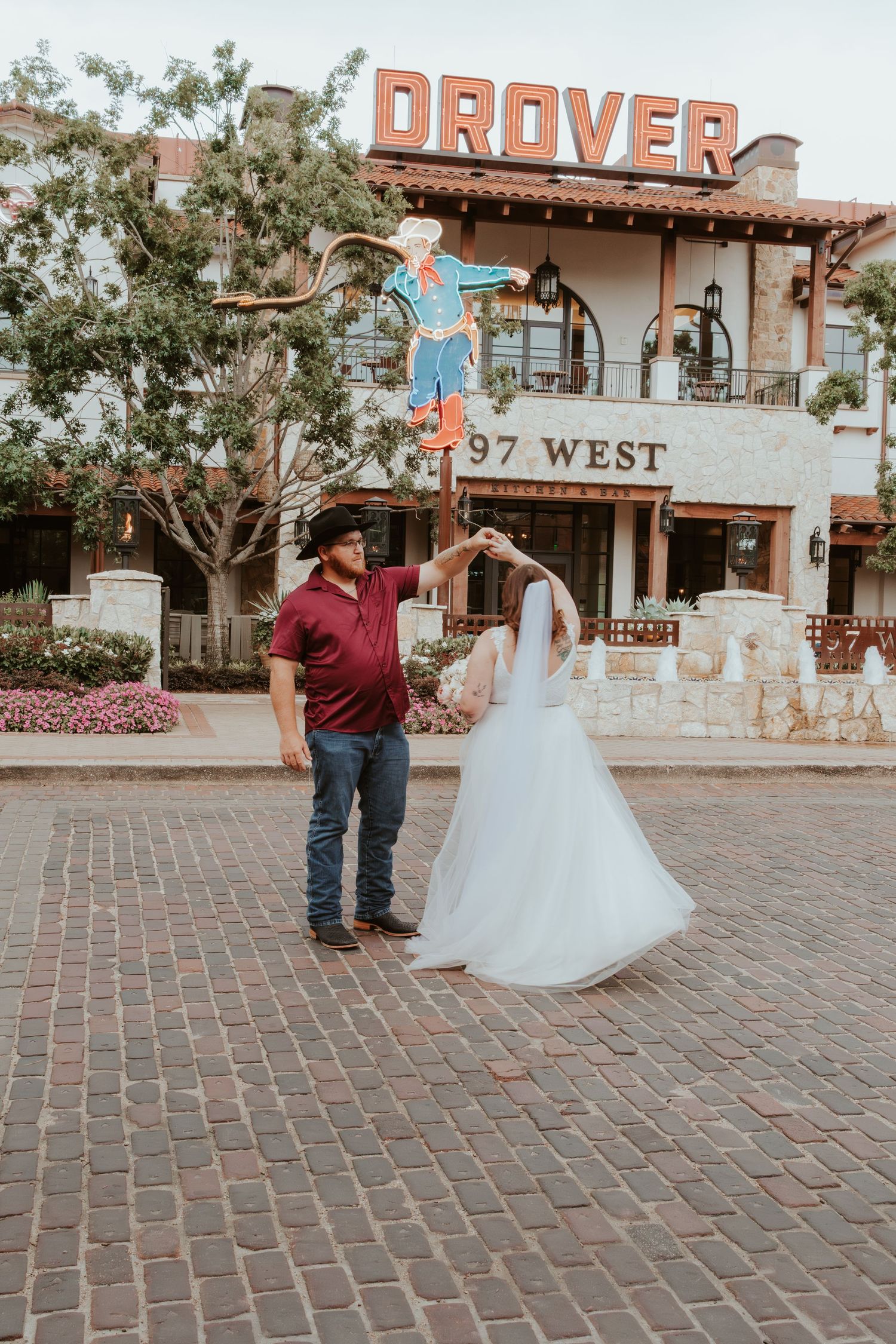 Newlyweds pose in front of Drover restaurant sign in Fort Worth.