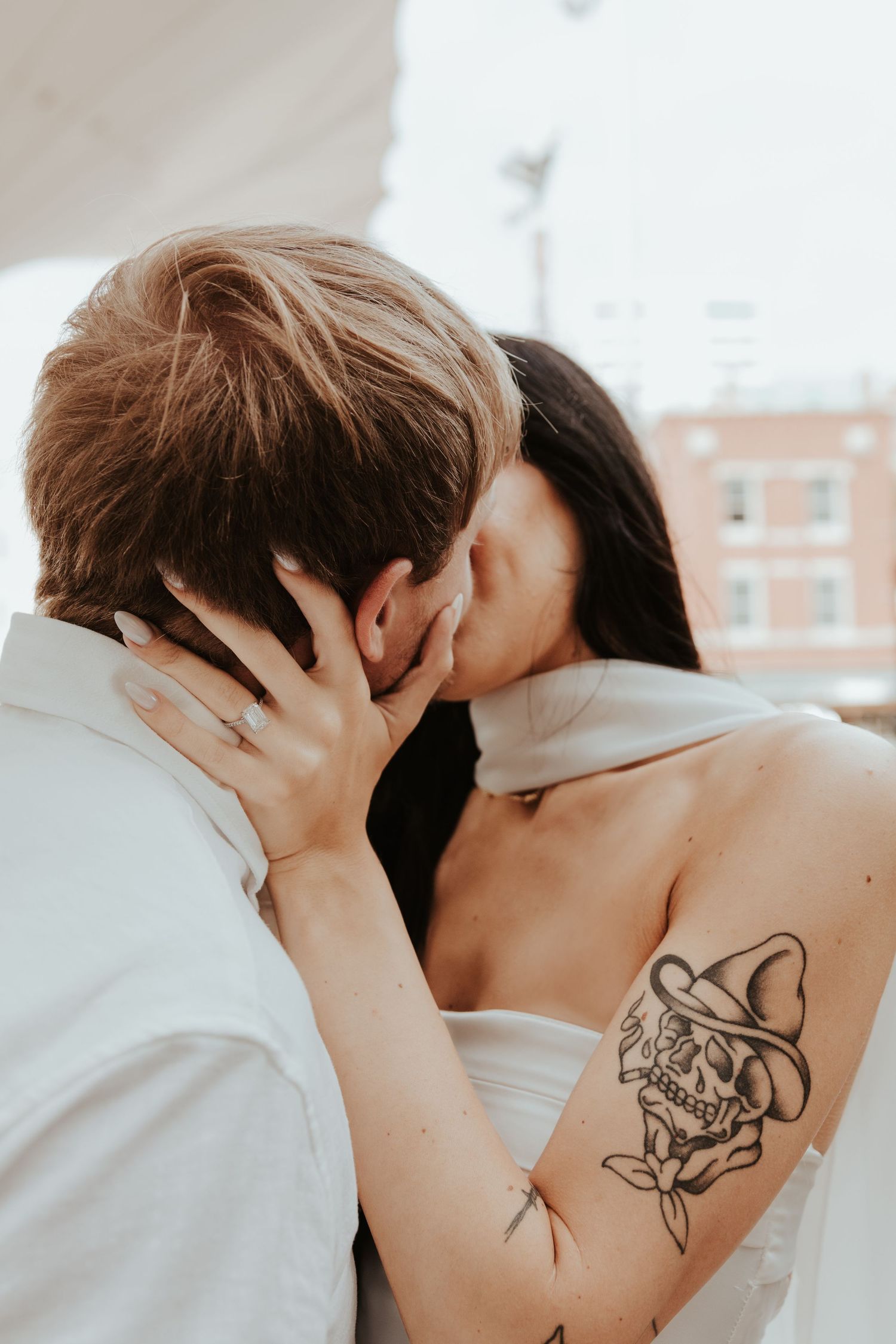 Tender intimate moment in a photo series showing a couple embracing, highlighting a visible back tattoo.