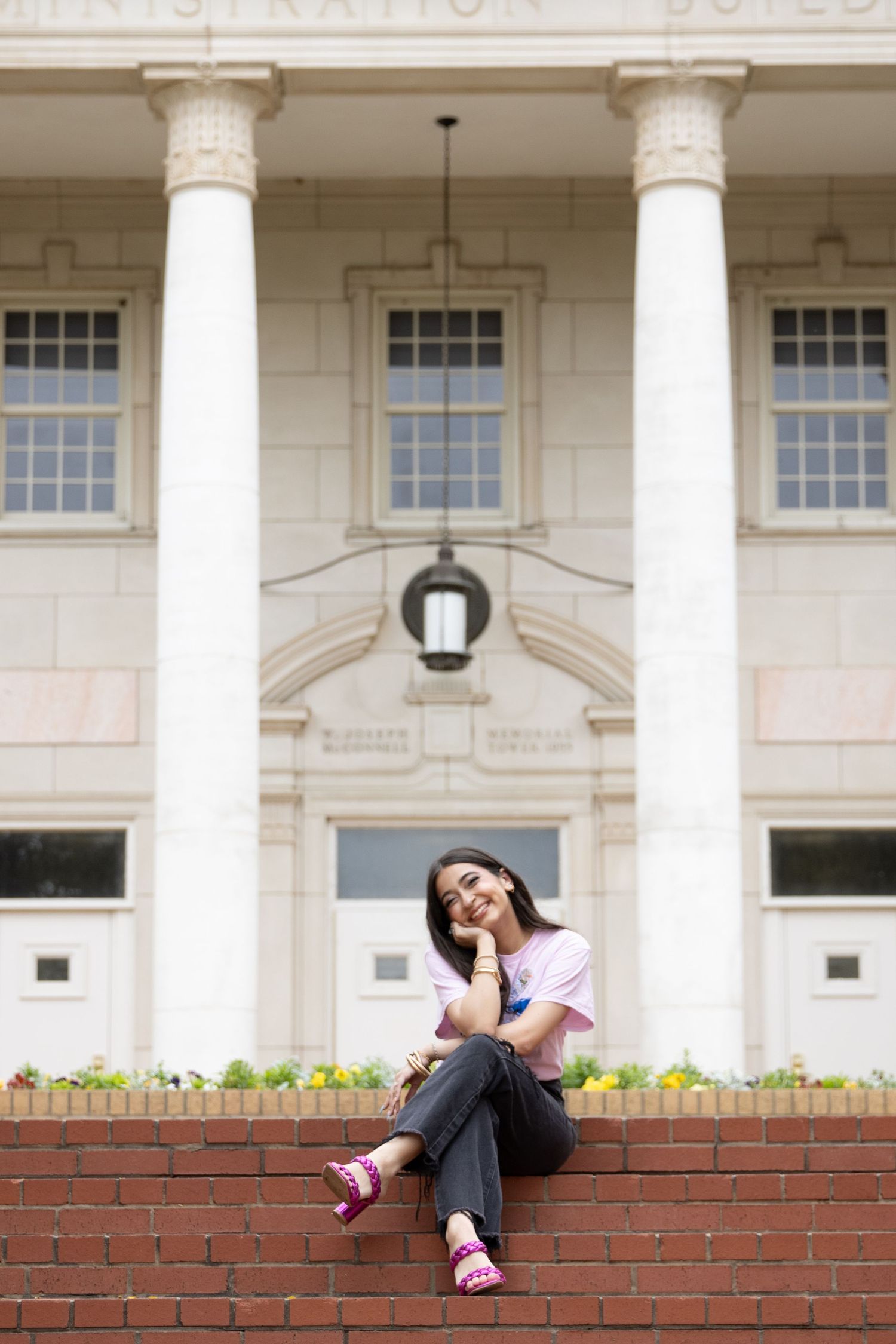 A relaxed pose on brick steps in front of a building with classical white columns.