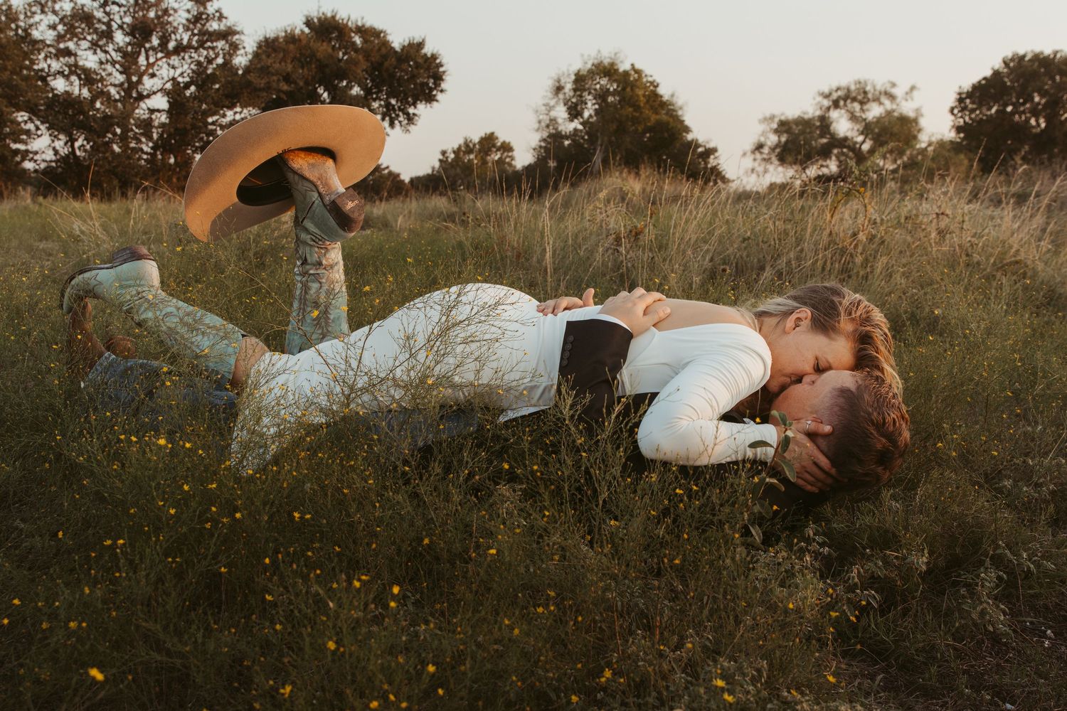 A series of artistic photographs showing a person lying in a grassy meadow at sunset with dramatic lighting. Engagement photographer DFW