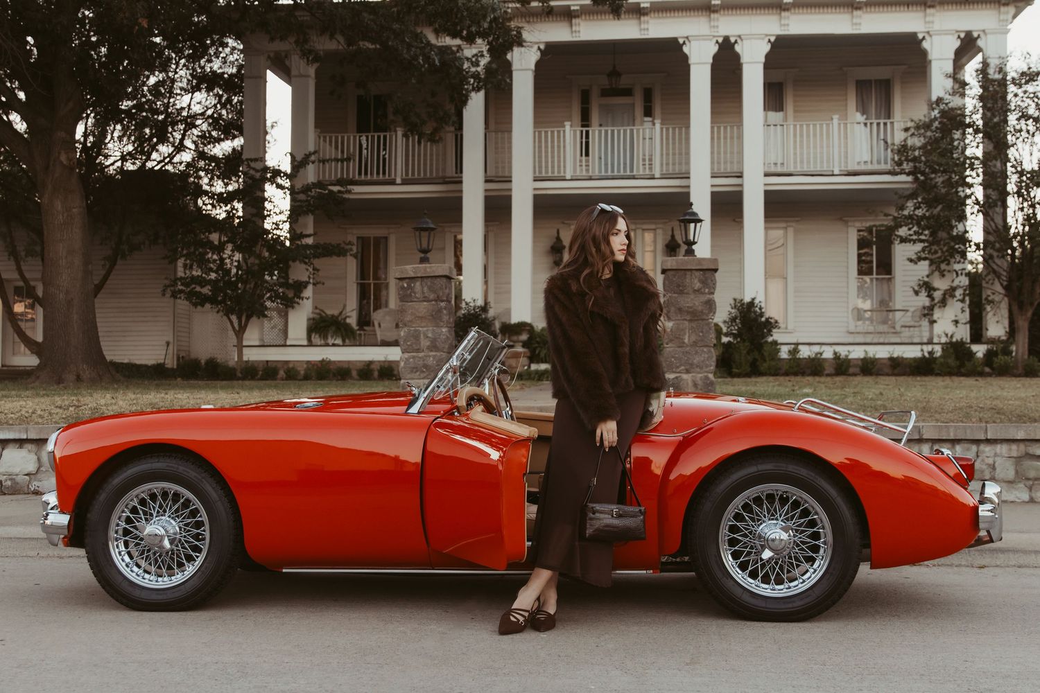 A vintage red sports car is parked on a street with classic wire wheels and elegant styling details.